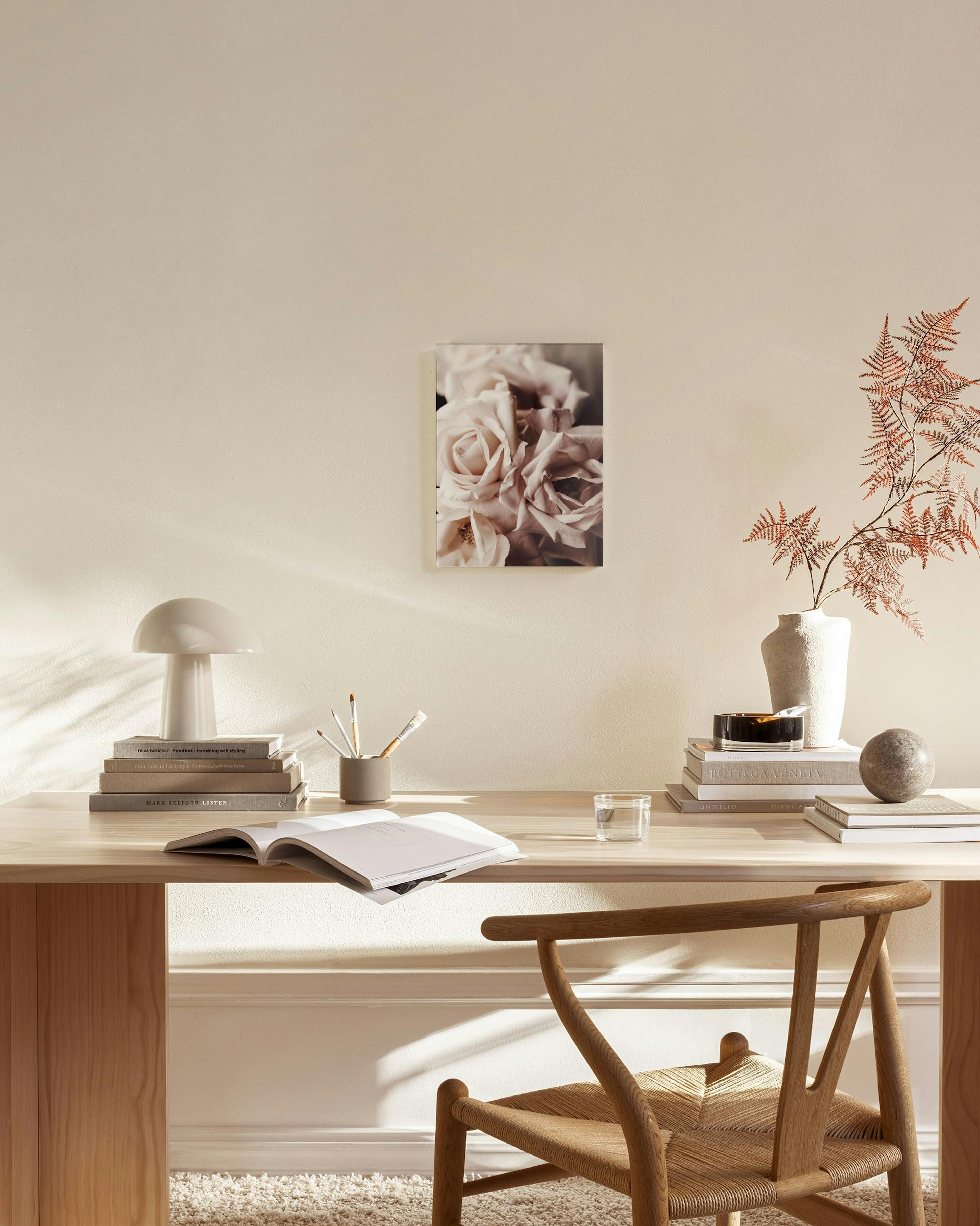 Stampa su tela di rose rosa pallido in un soggiorno moderno, sopra una panca in legno con lampada e decorazioni.