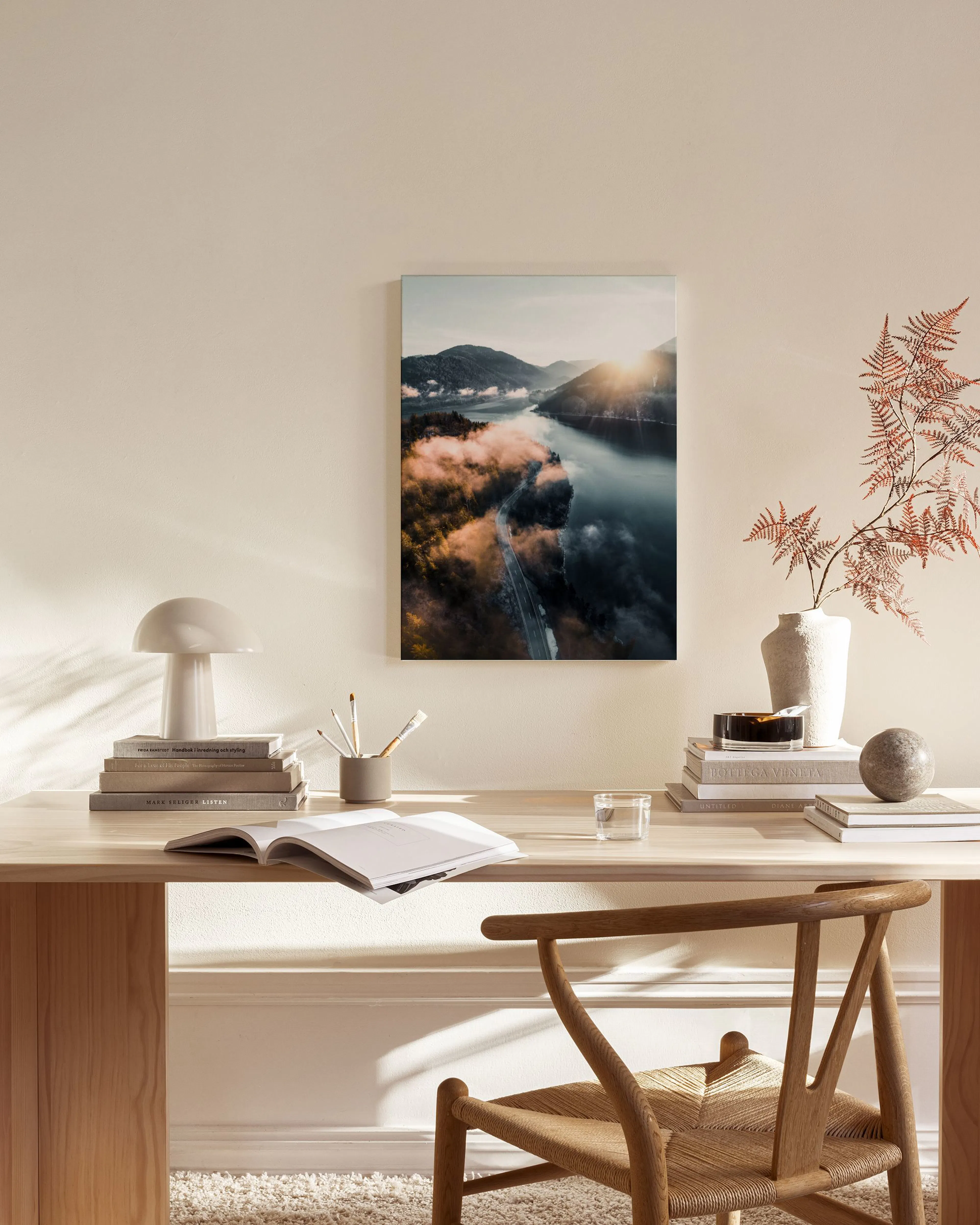 Leinwandbild mit Bergblick, Nebel, See und Straße im Sonnenaufgang, hängt über einem Holzregal im Wohnzimmer.