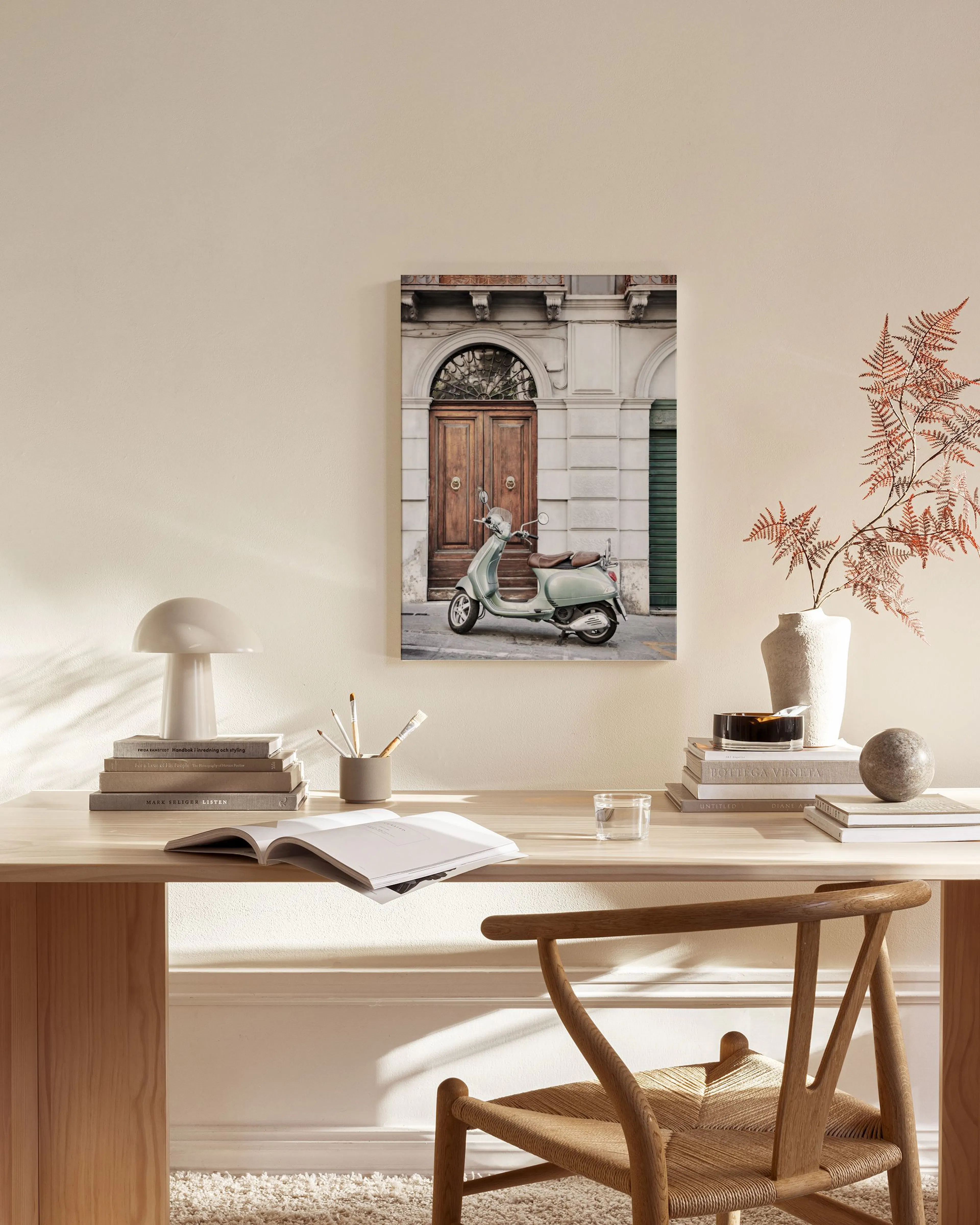 Canvas van een mintgroene Vespa voor een houten deur, hangend boven een houten dressoir in een minimalistische kamer.