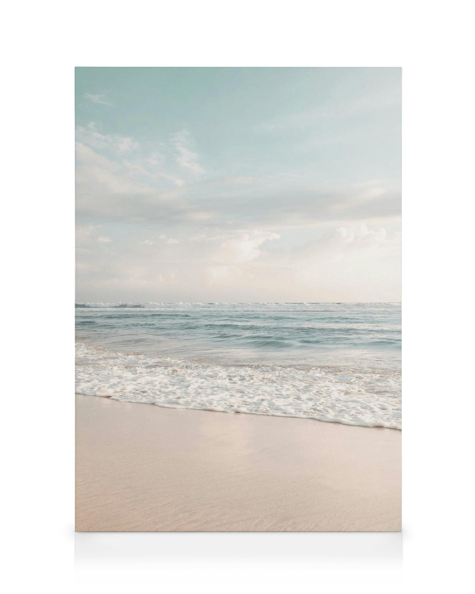 Tropical beach canvas print with light blue sky, white clouds, calm turquoise ocean waves, and light sandy shore.