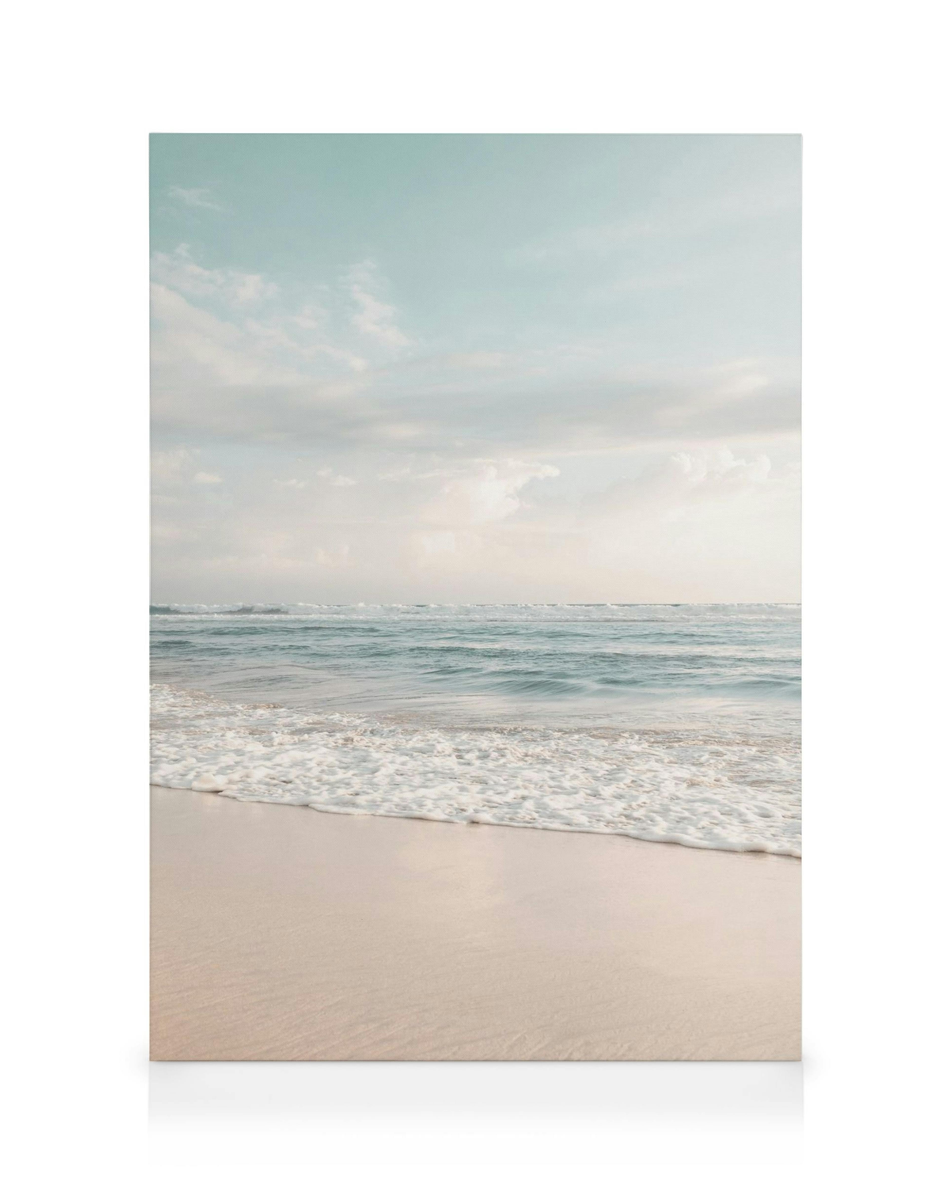 Tropical beach canvas print with light blue sky, white clouds, calm turquoise ocean waves, and light sandy shore.