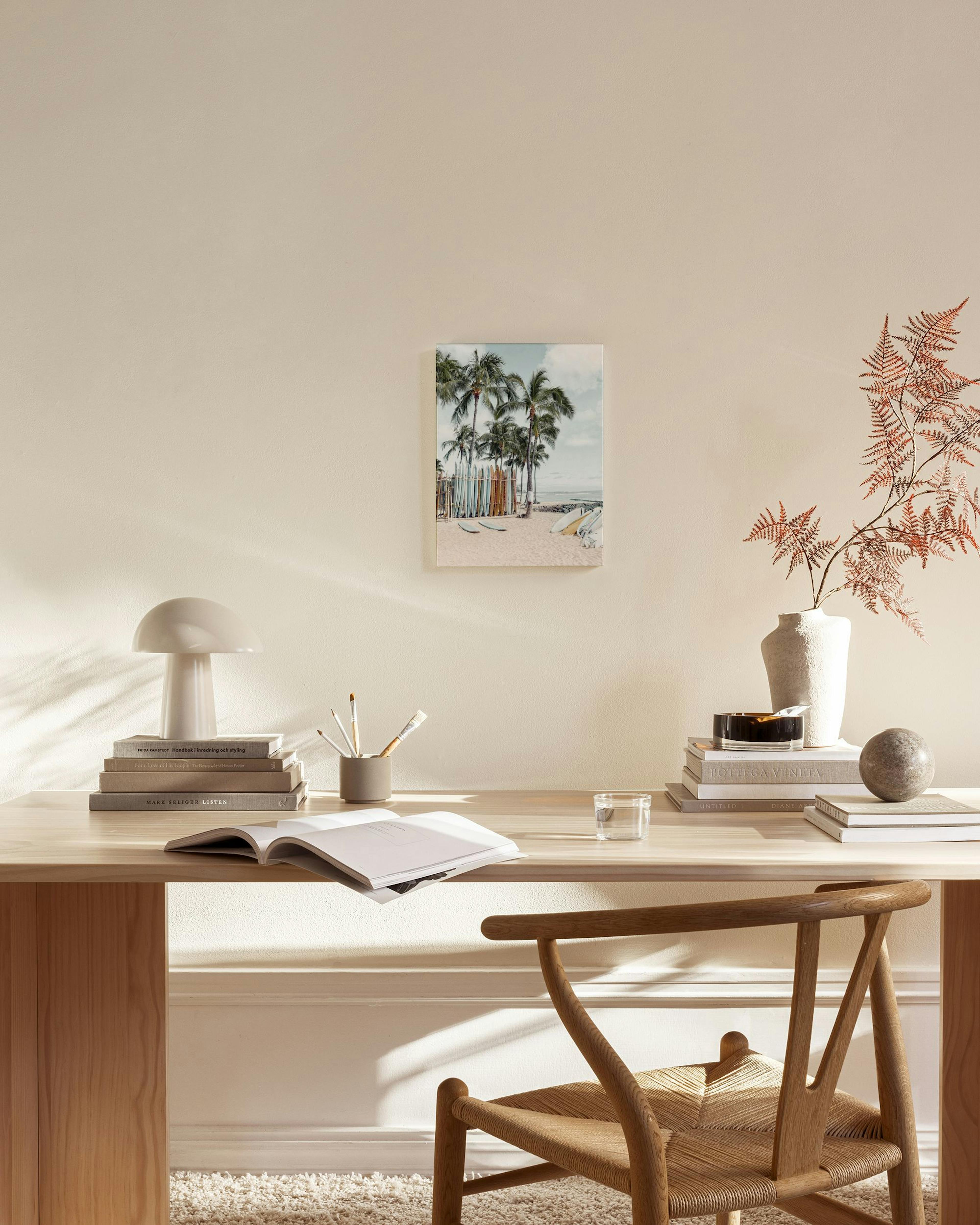 A tropical beach canvas print with palm trees and surfboards, hanging in a bright, minimalist living room.