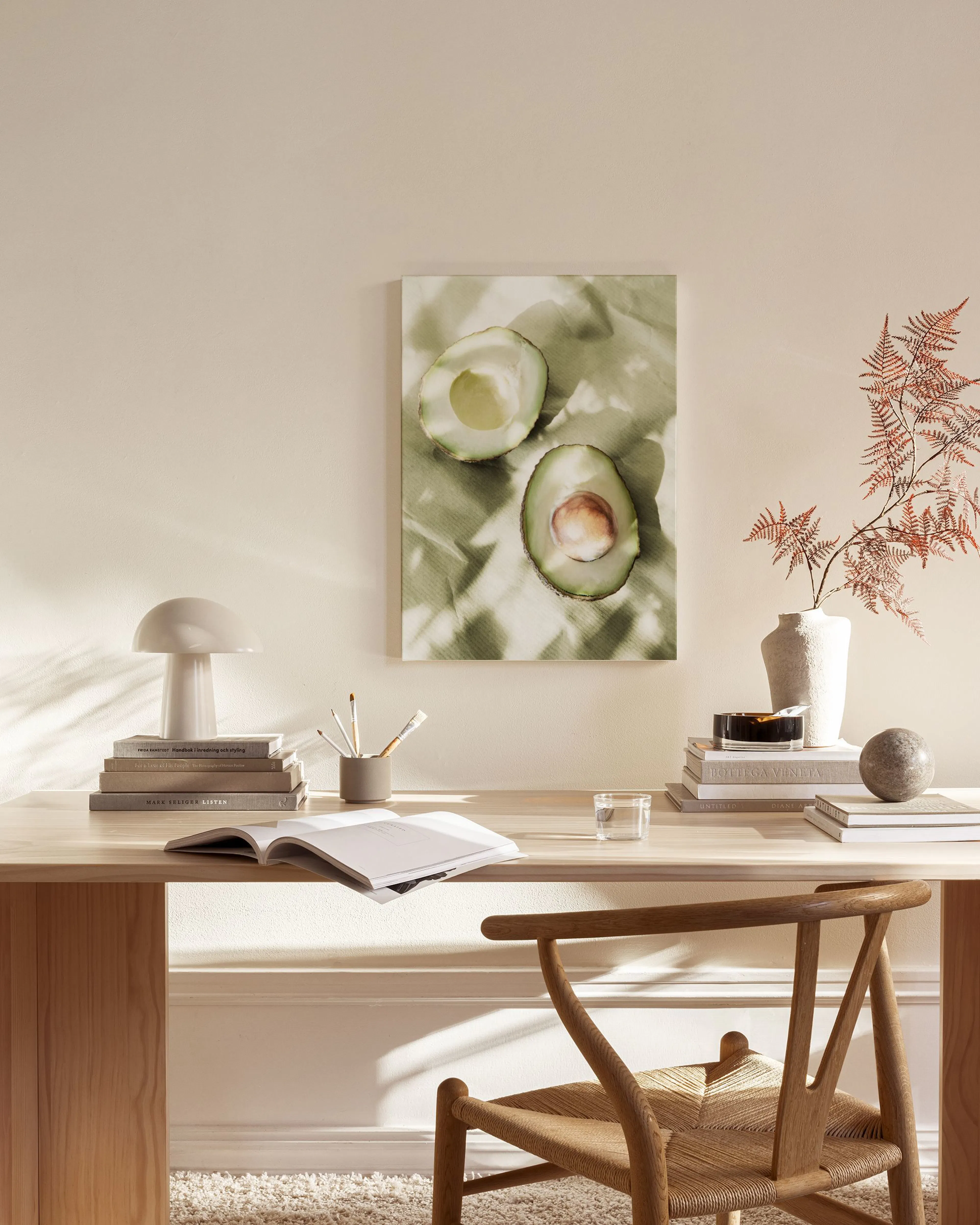 A canvas print of two halved avocados on a light green background, hanging in a minimalist living room.