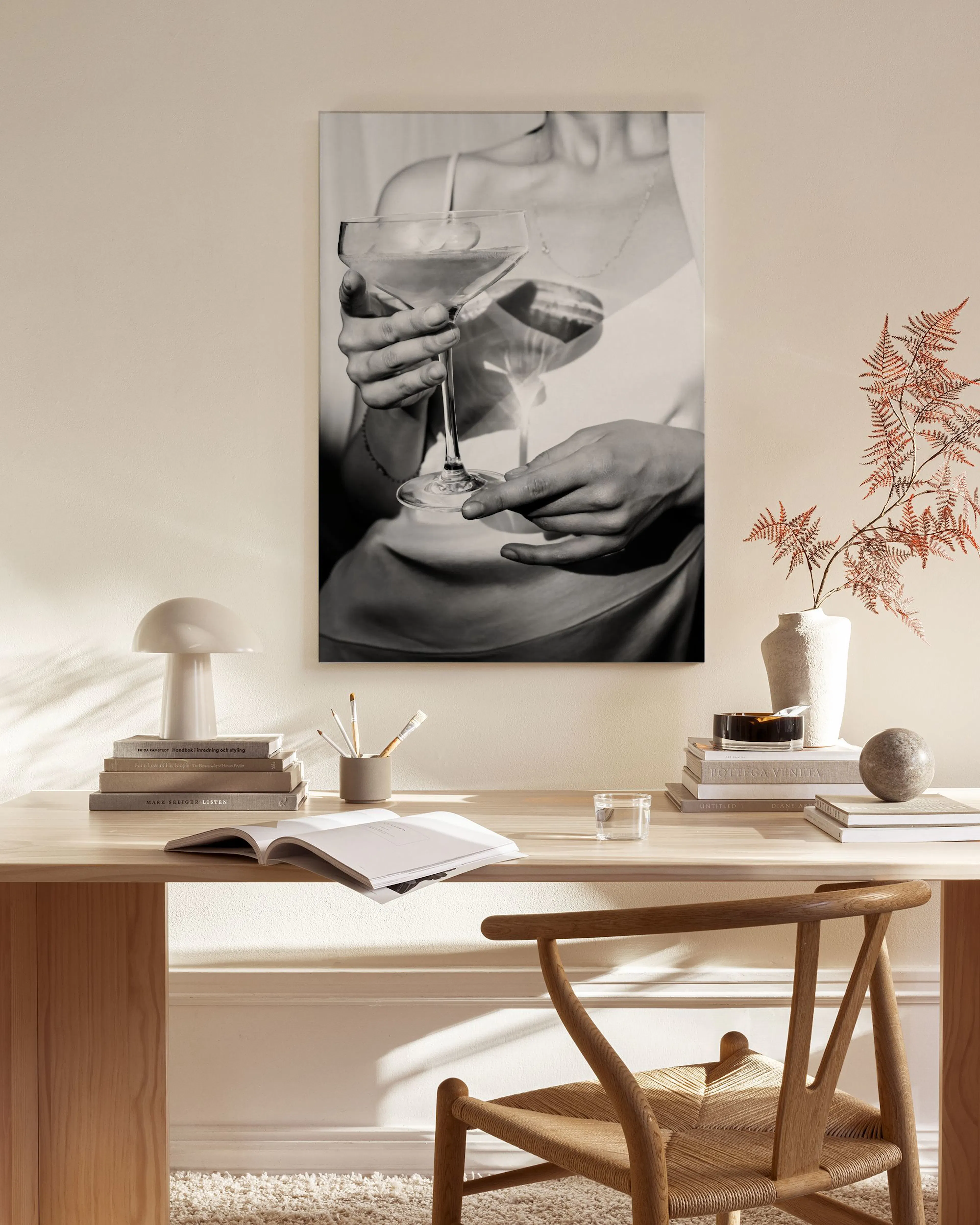 Toile noir et blanc dune femme tenant un verre à cocktail, accrochée dans un salon moderne aux tons neutres.