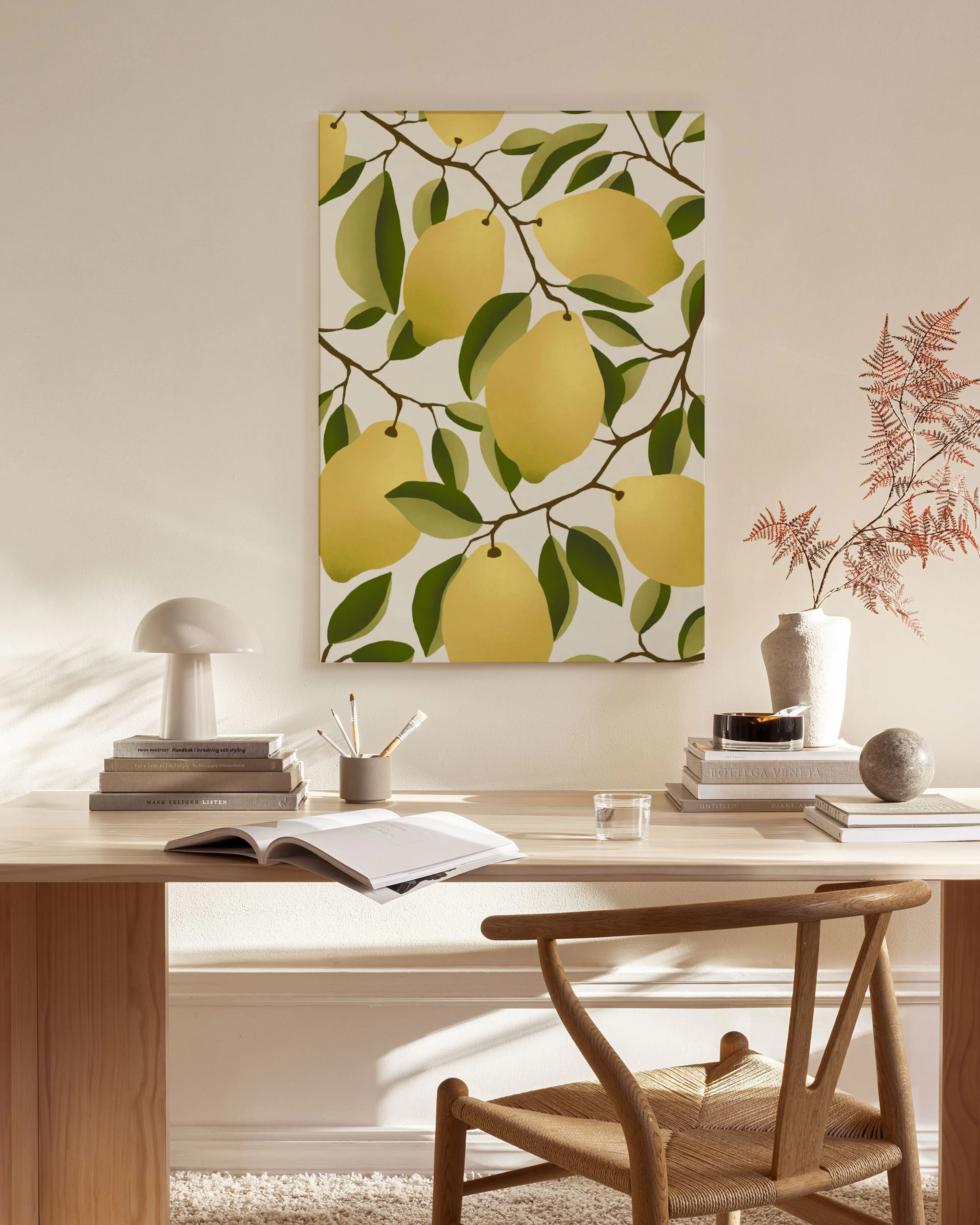 A canvas print of yellow lemons on green branches, hanging above a light wooden console in a bright living room.