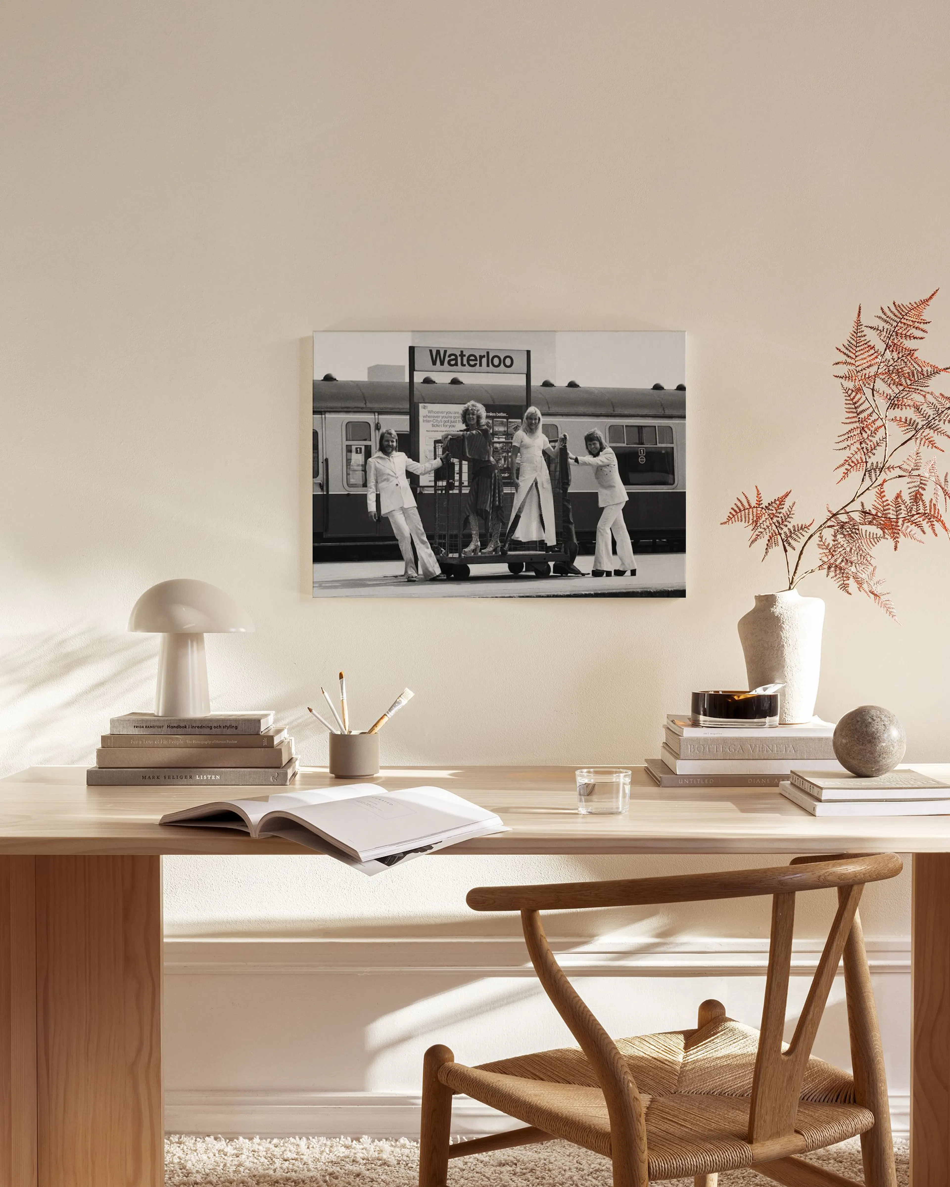 Toile noir et blanc de quatre personnes sur un quai de gare, affichée dans un salon moderne.