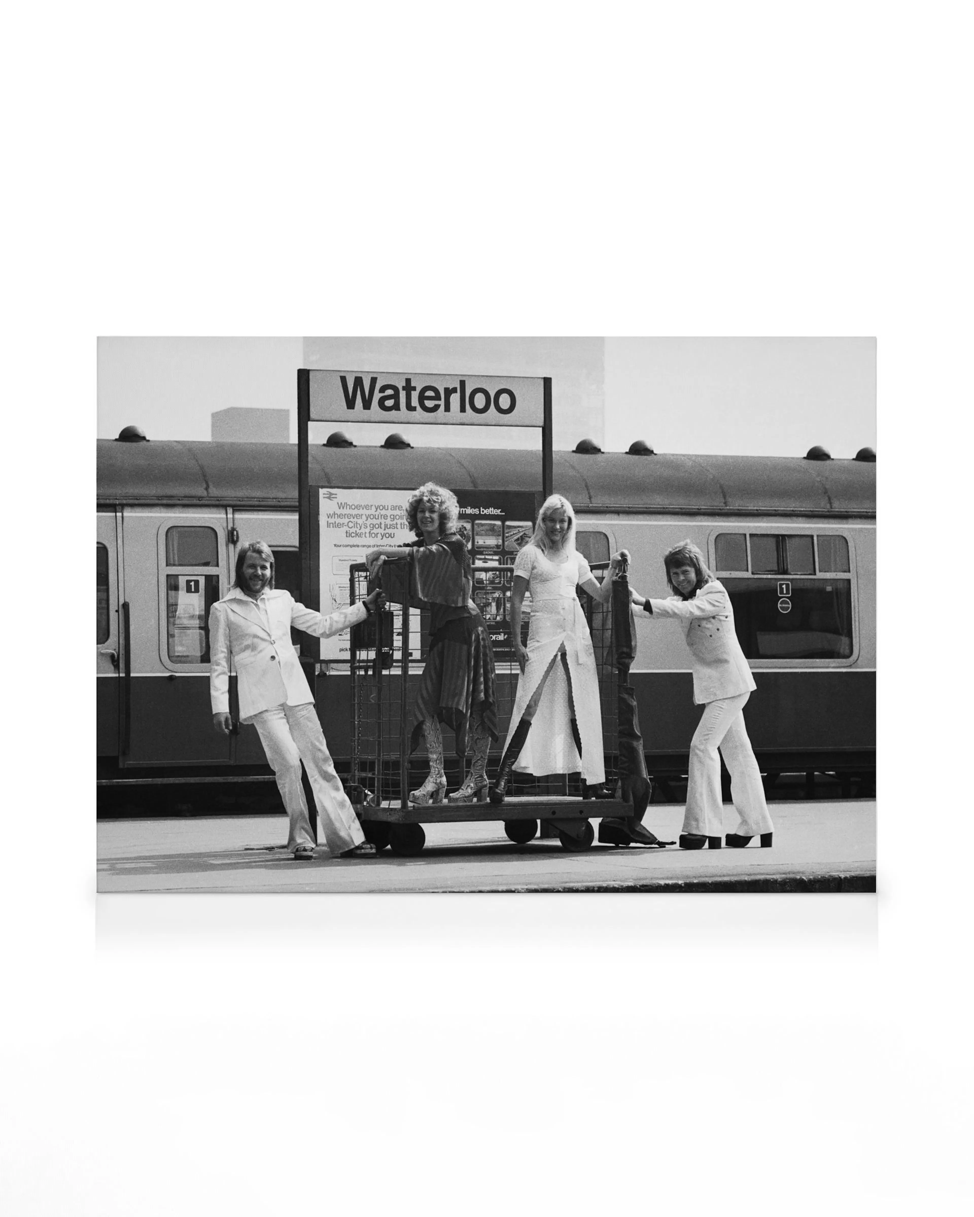 Toile ABBA noir et blanc de quatre personnes élégantes des années 70 posant avec des bagages à la gare de Waterloo.