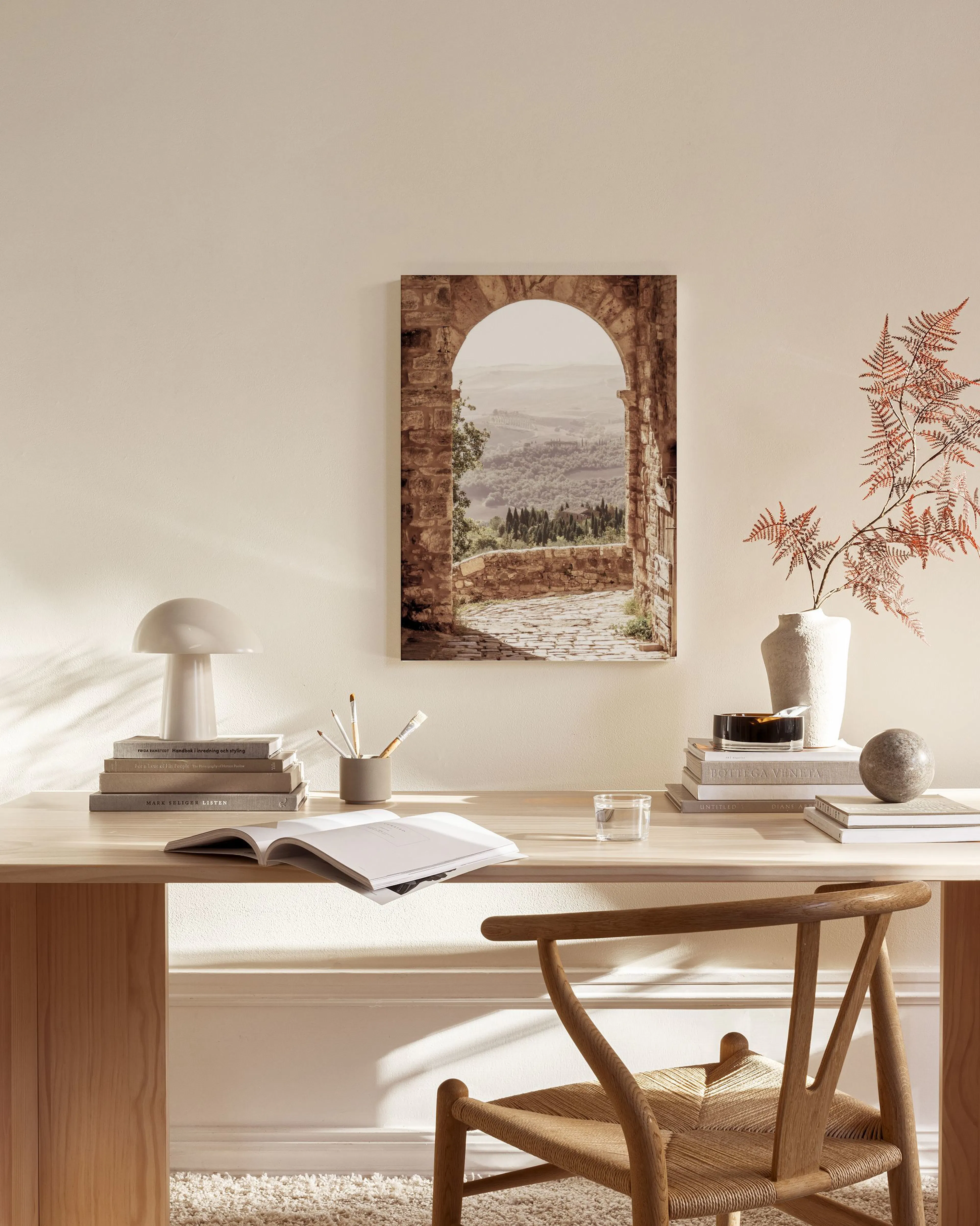 A Tuscan archway print revealing a distant valley view, hanging in a minimalist living room above a wooden console.