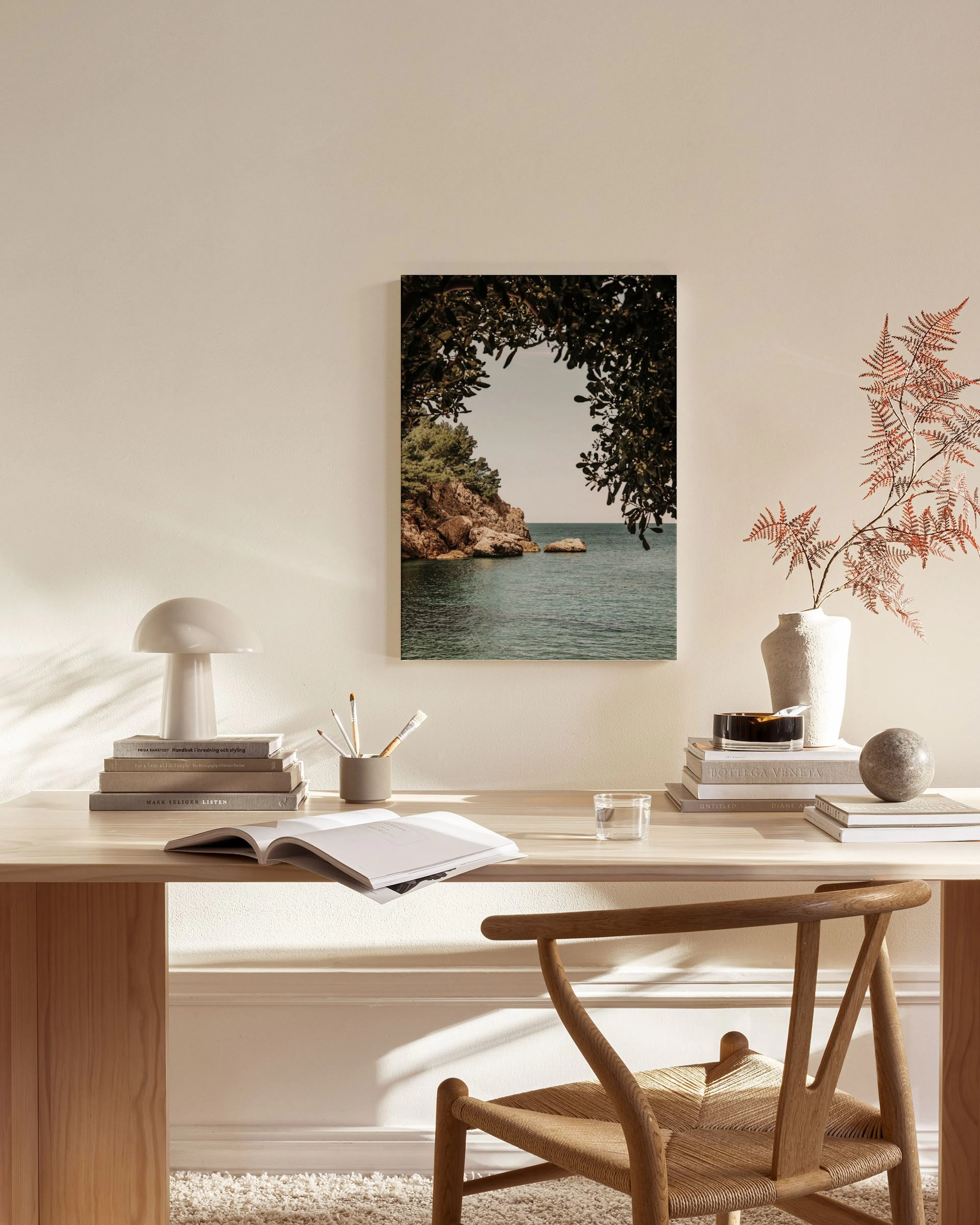 Toile murale paysage marin avec rochers et feuillage au-dessus dun banc en bois, table basse et tapis dans un salon moderne.