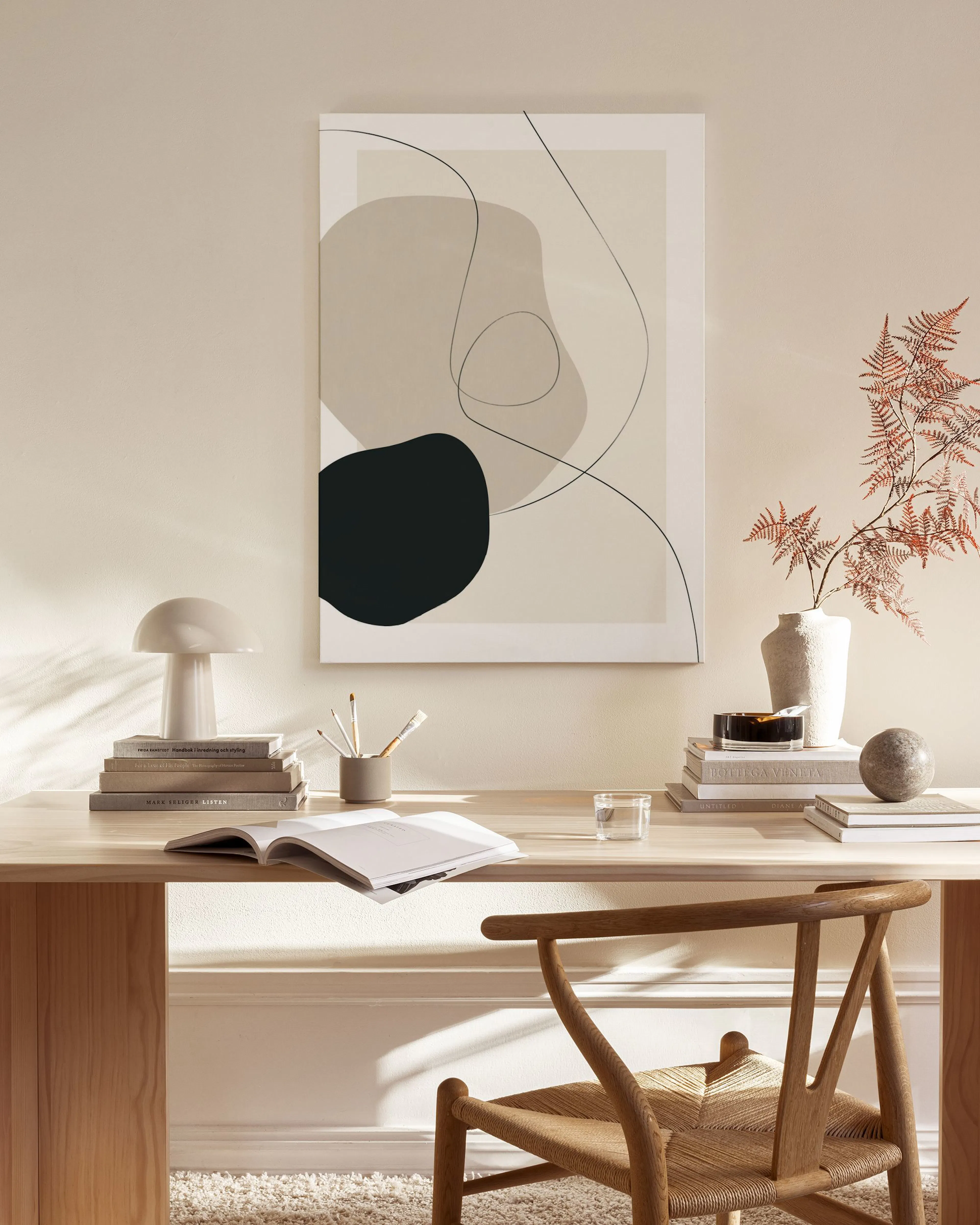 Toile abstraite aux formes organiques beige et noire, avec des lignes fines, suspendue dans un salon moderne aux tons clairs.