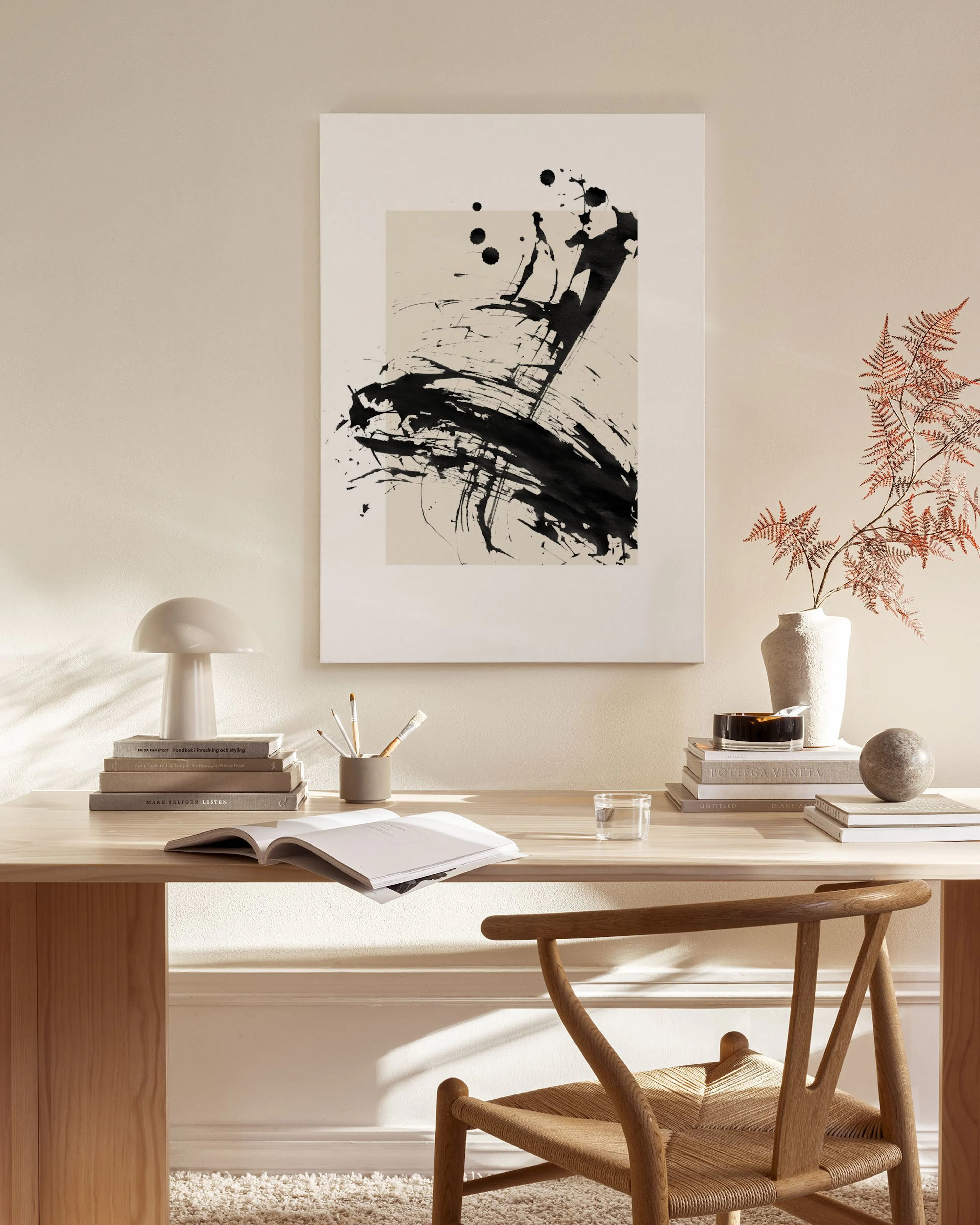 Leinwandbild mit schwarzem Pinselstrich und Spritzern auf hellem Hintergrund, im modernen Wohnzimmer über einem Sideboard.