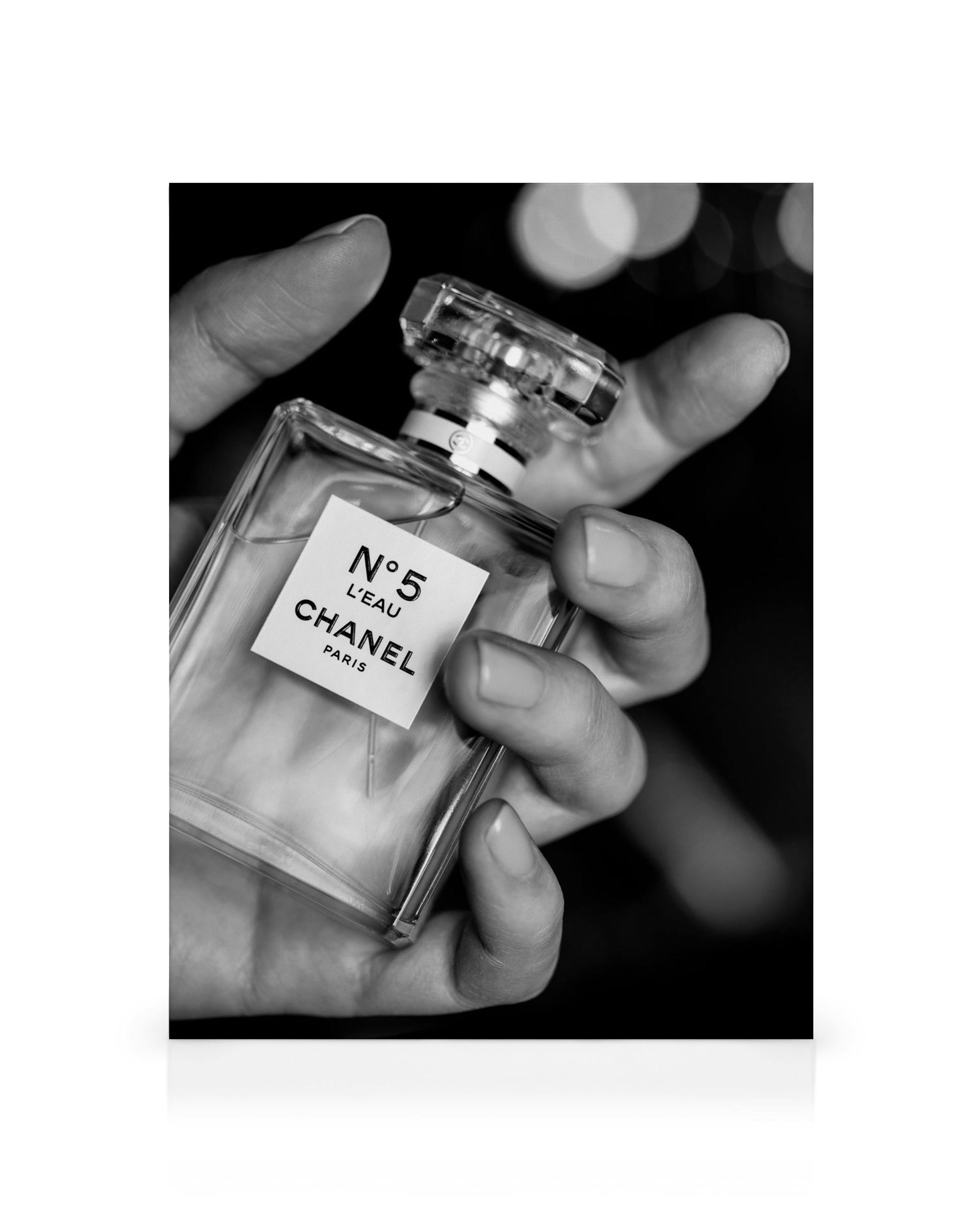 Ασπρόμαυρος καμβάς με χέρι που κρατάει άρωμα Chanel No5, ιδανικός για διακόσμηση σπιτιού.