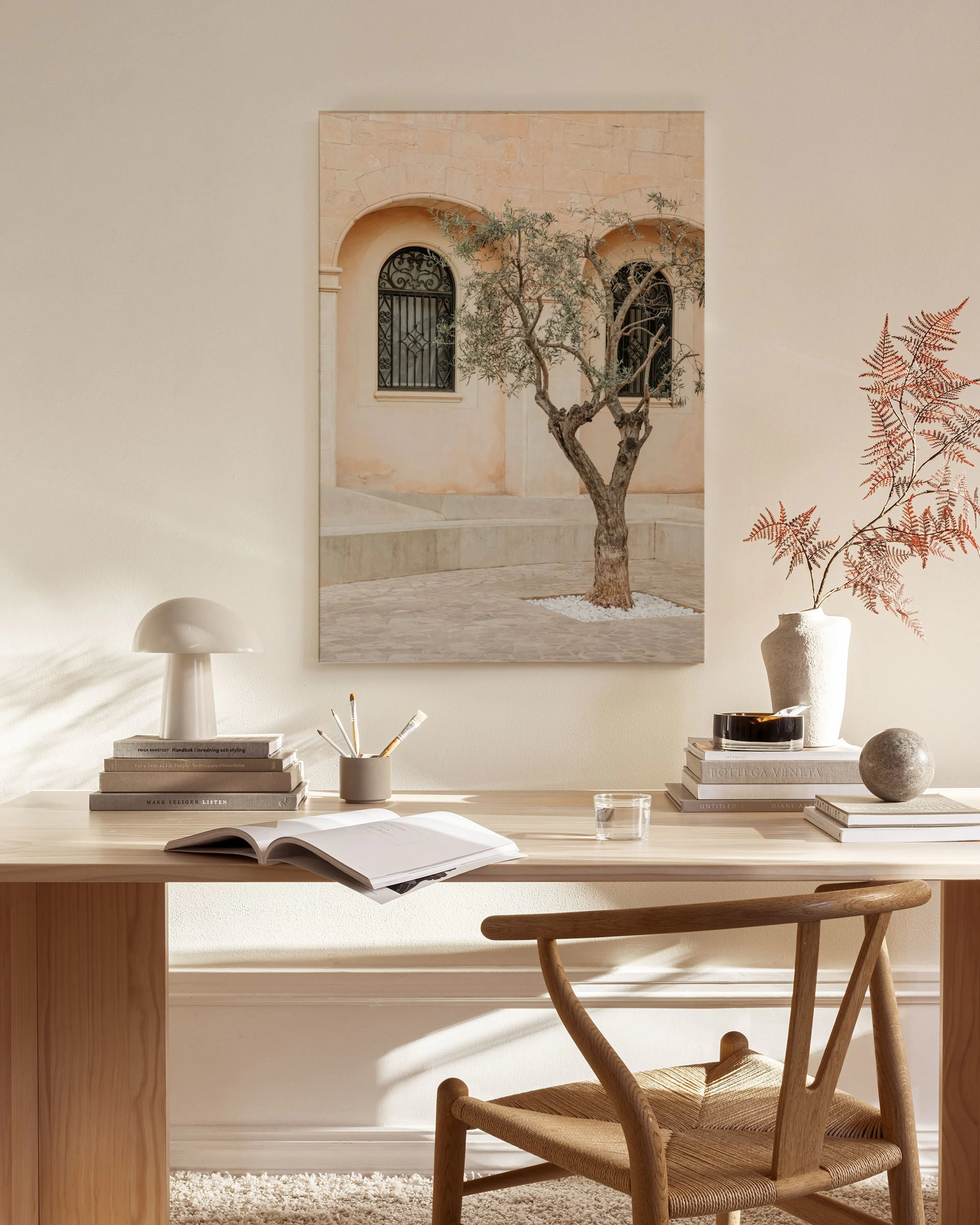 Canvas print of an olive tree in front of an old building, displayed in a bright living room.