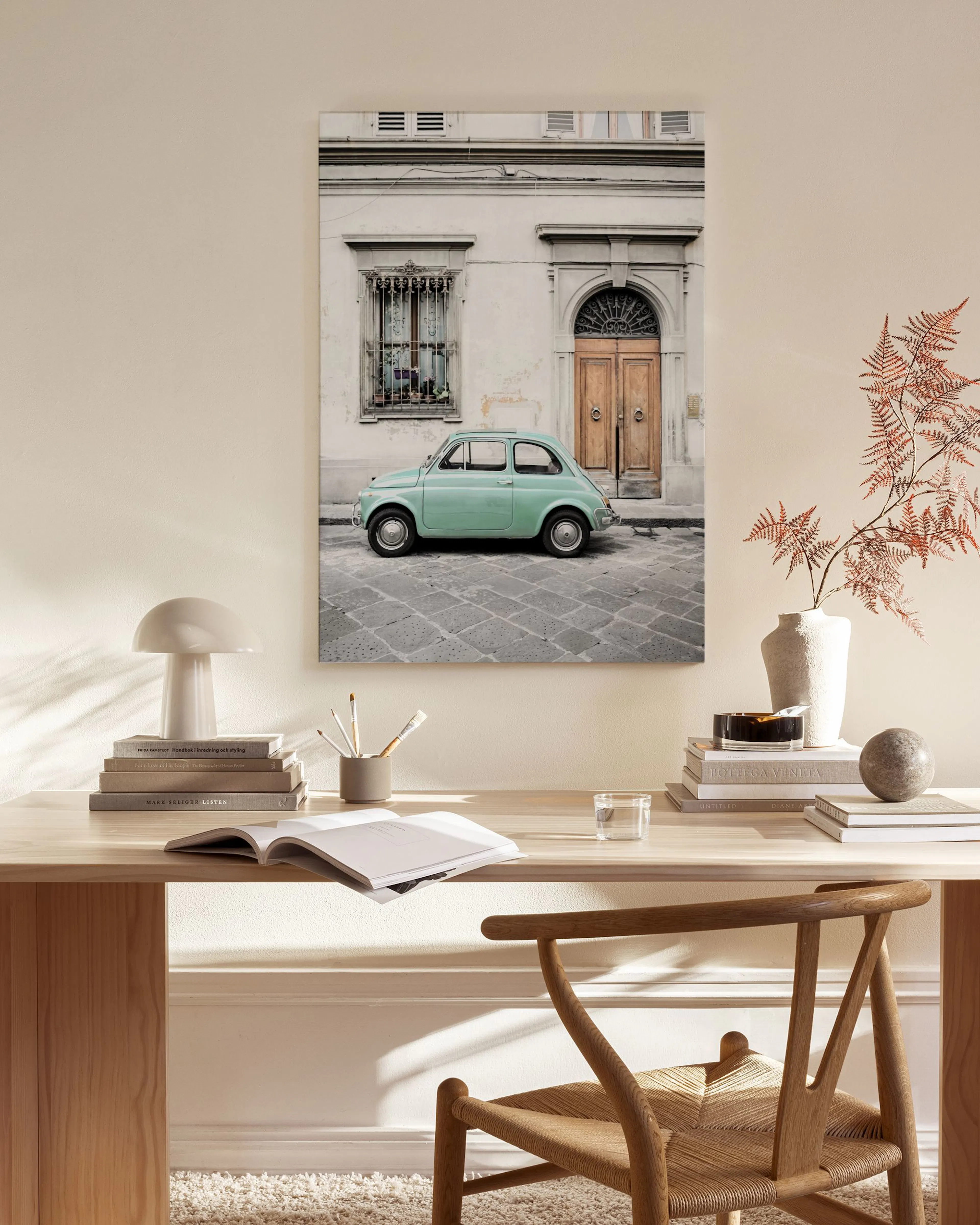 Canvas van een groene oldtimer voor een gebouw, hangend in een moderne, lichte woonkamer boven een houten meubel.