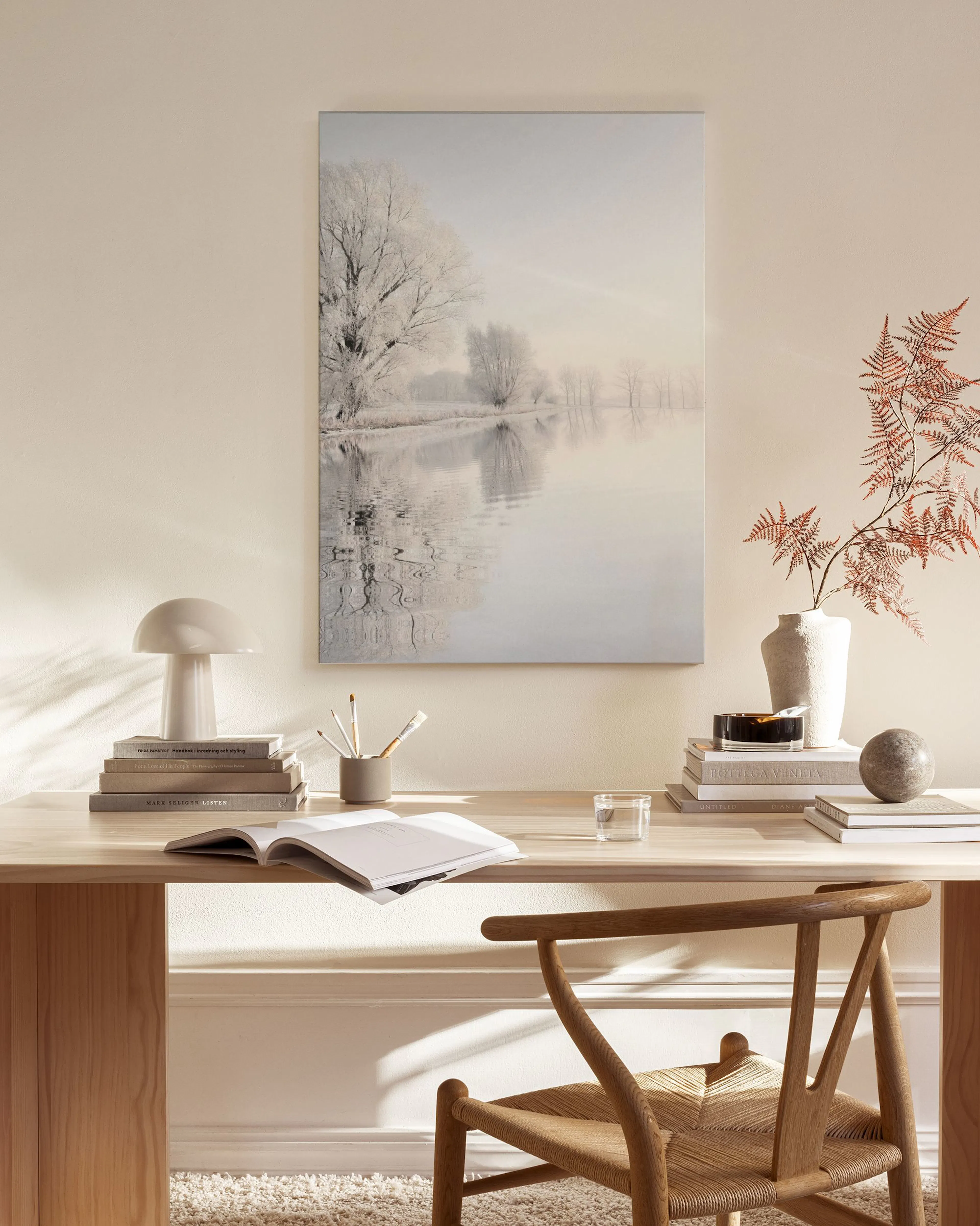 Leinwandbild einer Winterlandschaft mit gefrorenen Bäumen und einem See, in einem hellen Wohnzimmer über einem Sideboard.