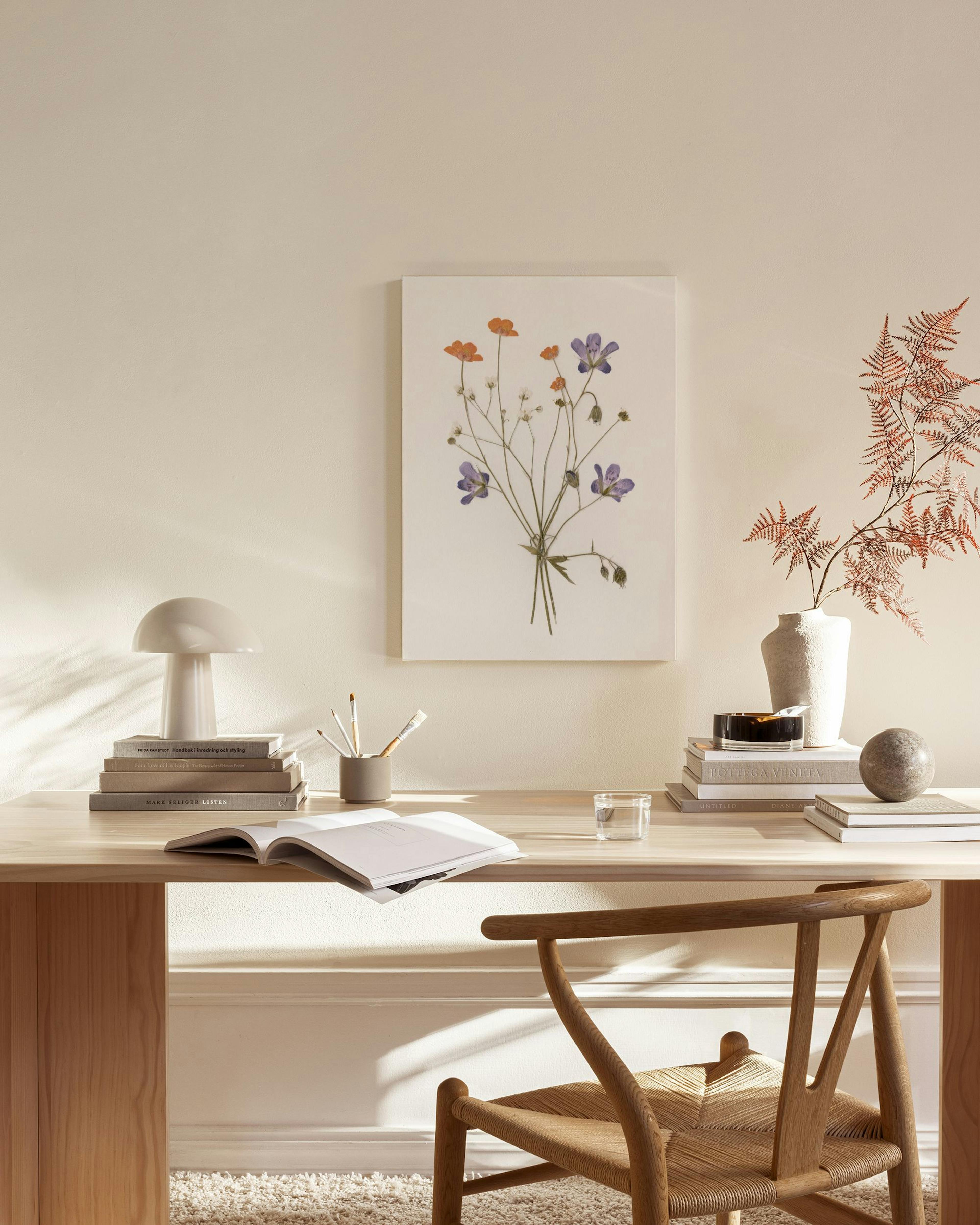 Toile florale de fleurs violettes et oranges suspendue dans un salon contemporain au-dessus dune table basse et dun fauteuil.