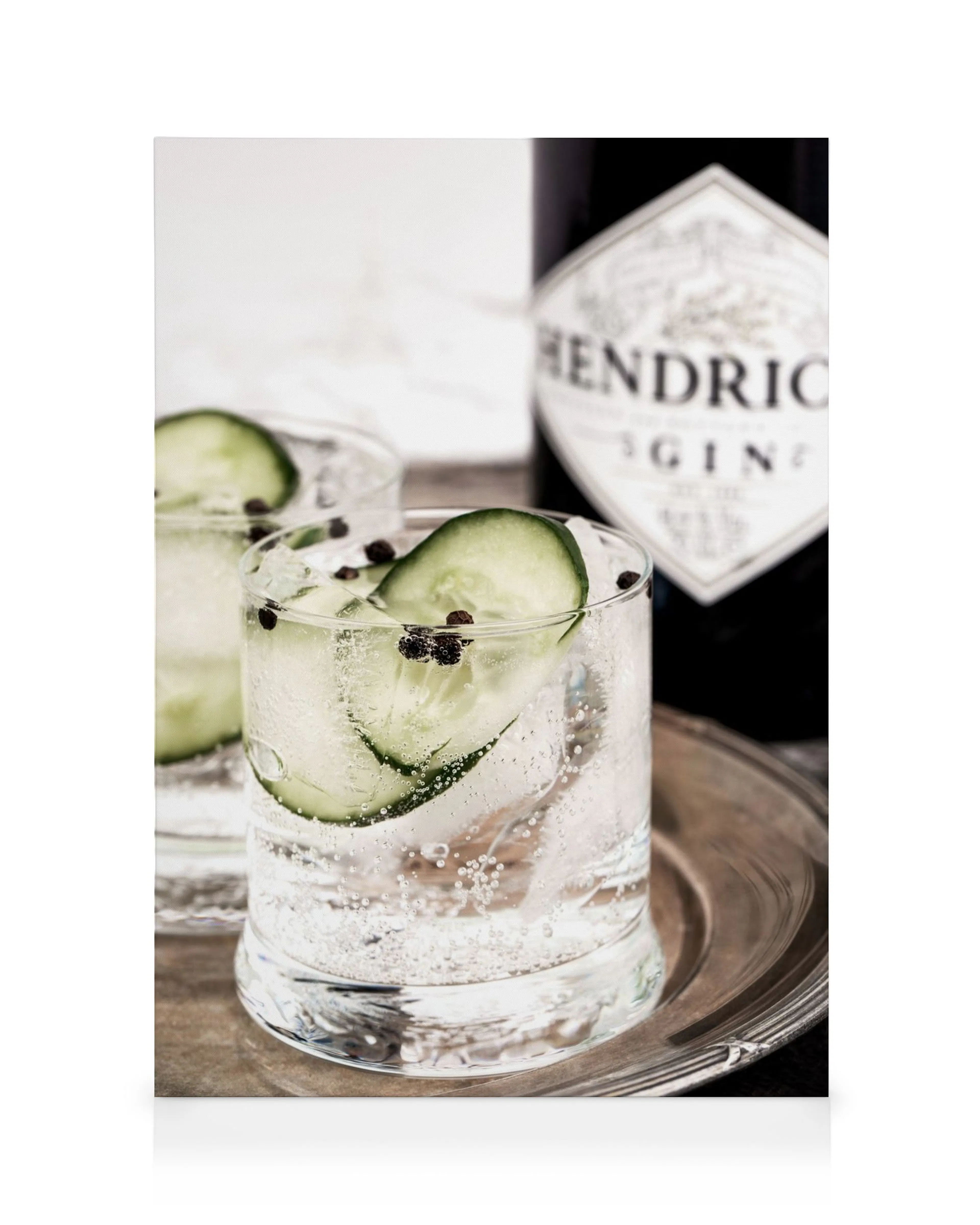 Gin and Tonic drink with cucumber, ice, and black seeds; Hendricks Gin bottle in the background on canvas print.