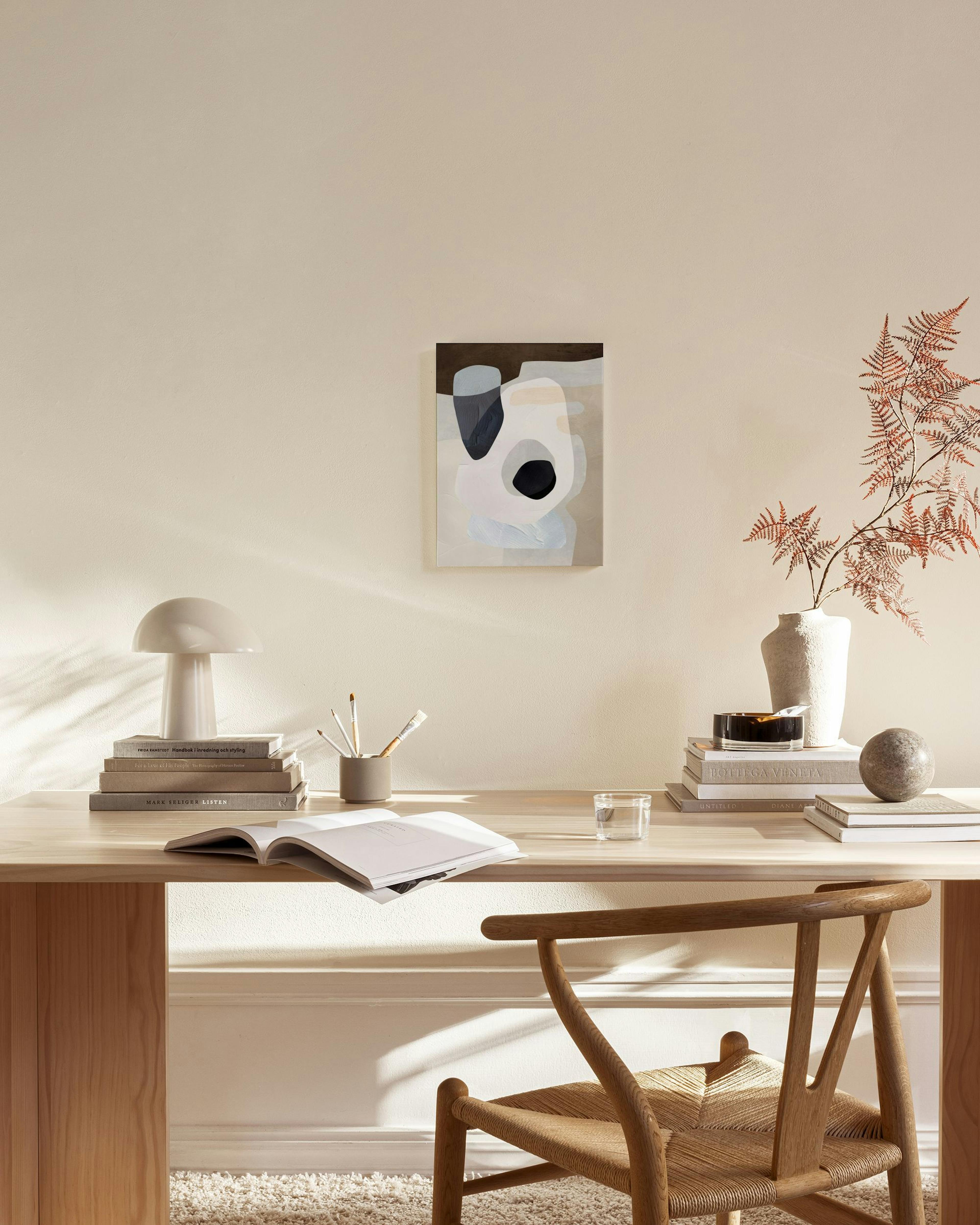 Canvas met organische vormen in zwart, grijs, wit en beige, hangend in een moderne woonkamer boven een houten meubel.