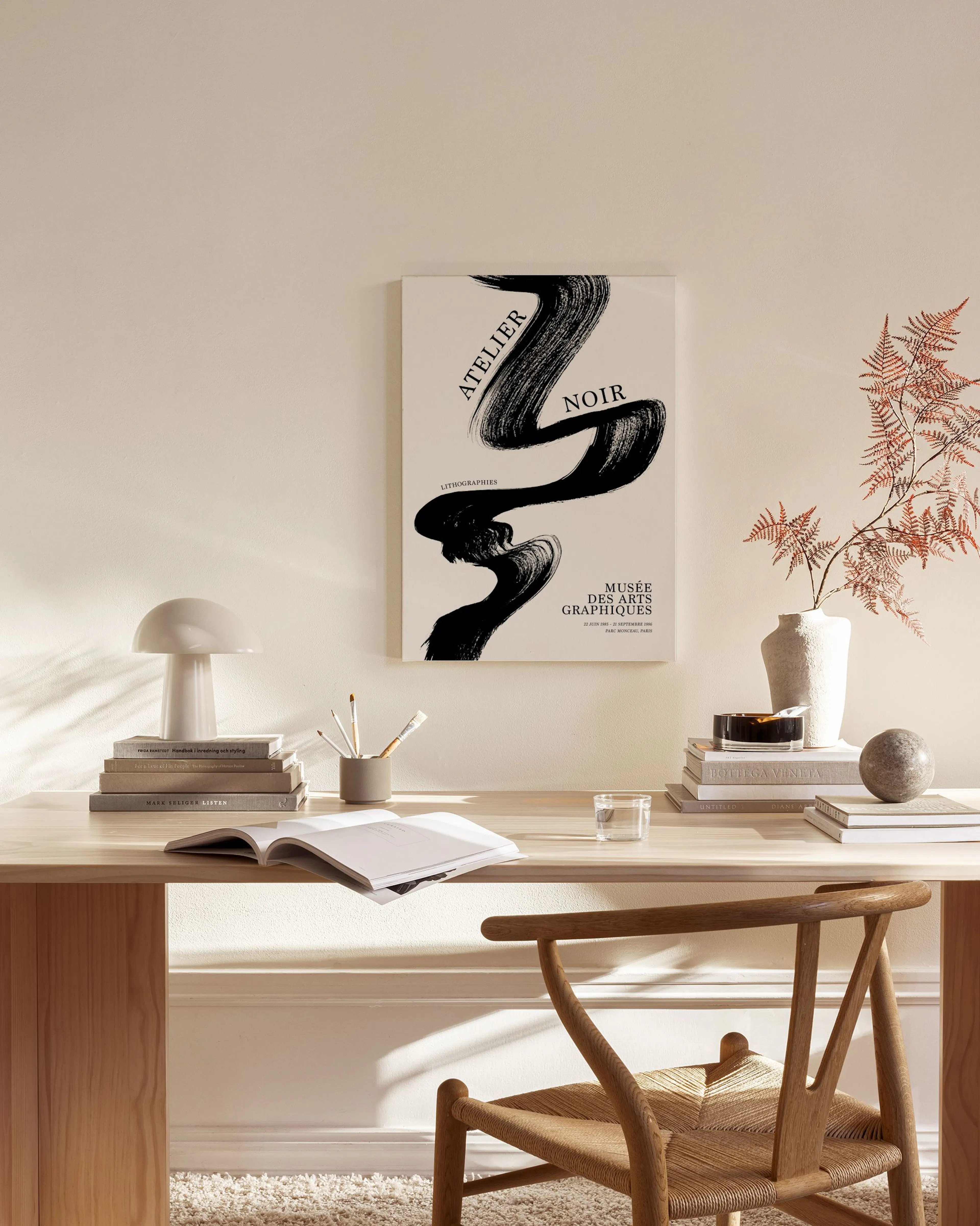 Leinwandbild mit schwarzem, geschwungenem Pinselstrich auf beigem Grund, hängt in einem hellen Wohnzimmer über einem Sideboard.