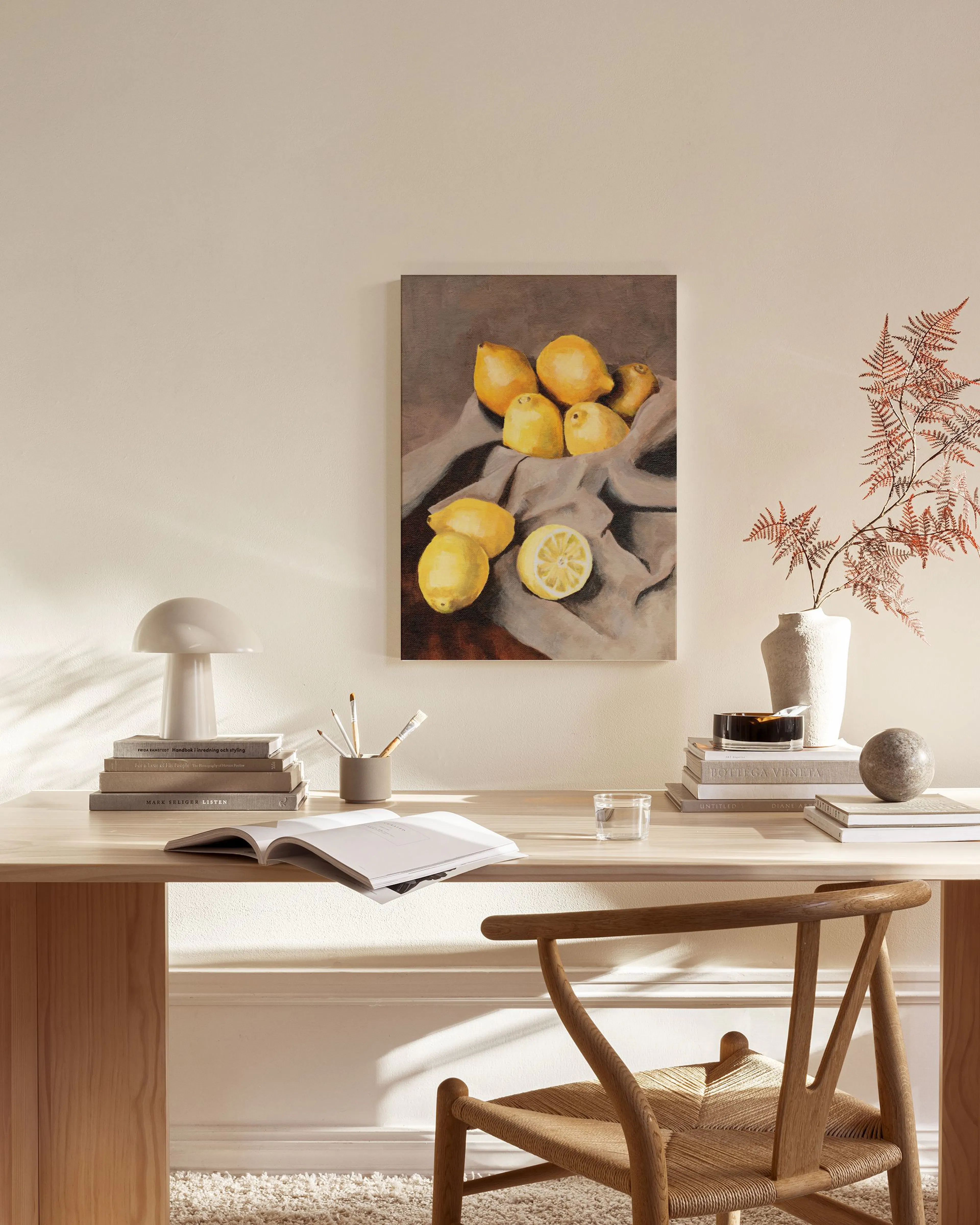 Leinwandbild mit Zitronen auf grauem Tuch, über einem Sideboard mit Lampe und Bücher im Wohnzimmer.