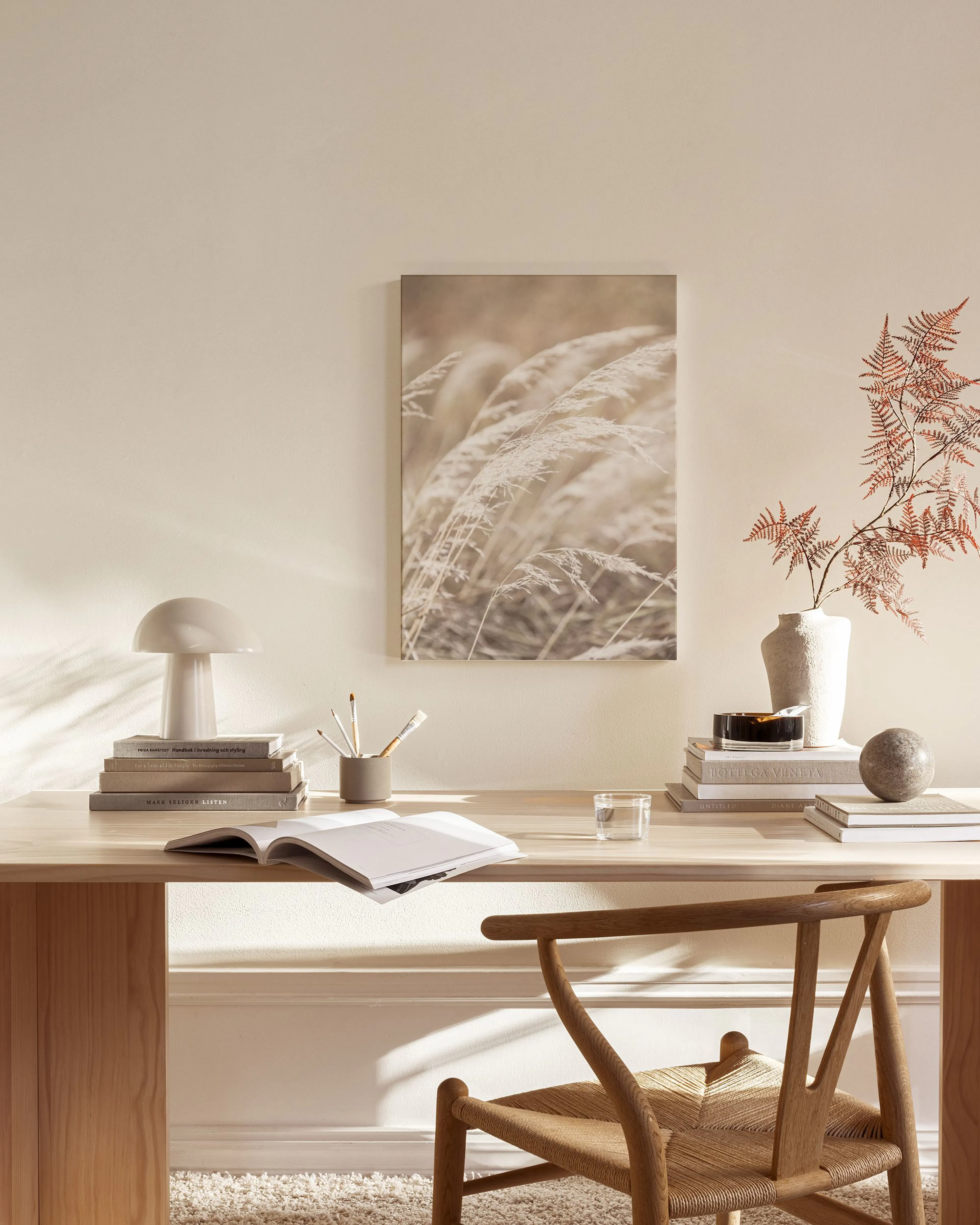 Leinwandbild mit weichem, beigem Pampasgras in einem hellen Wohnzimmer über einem Sideboard.