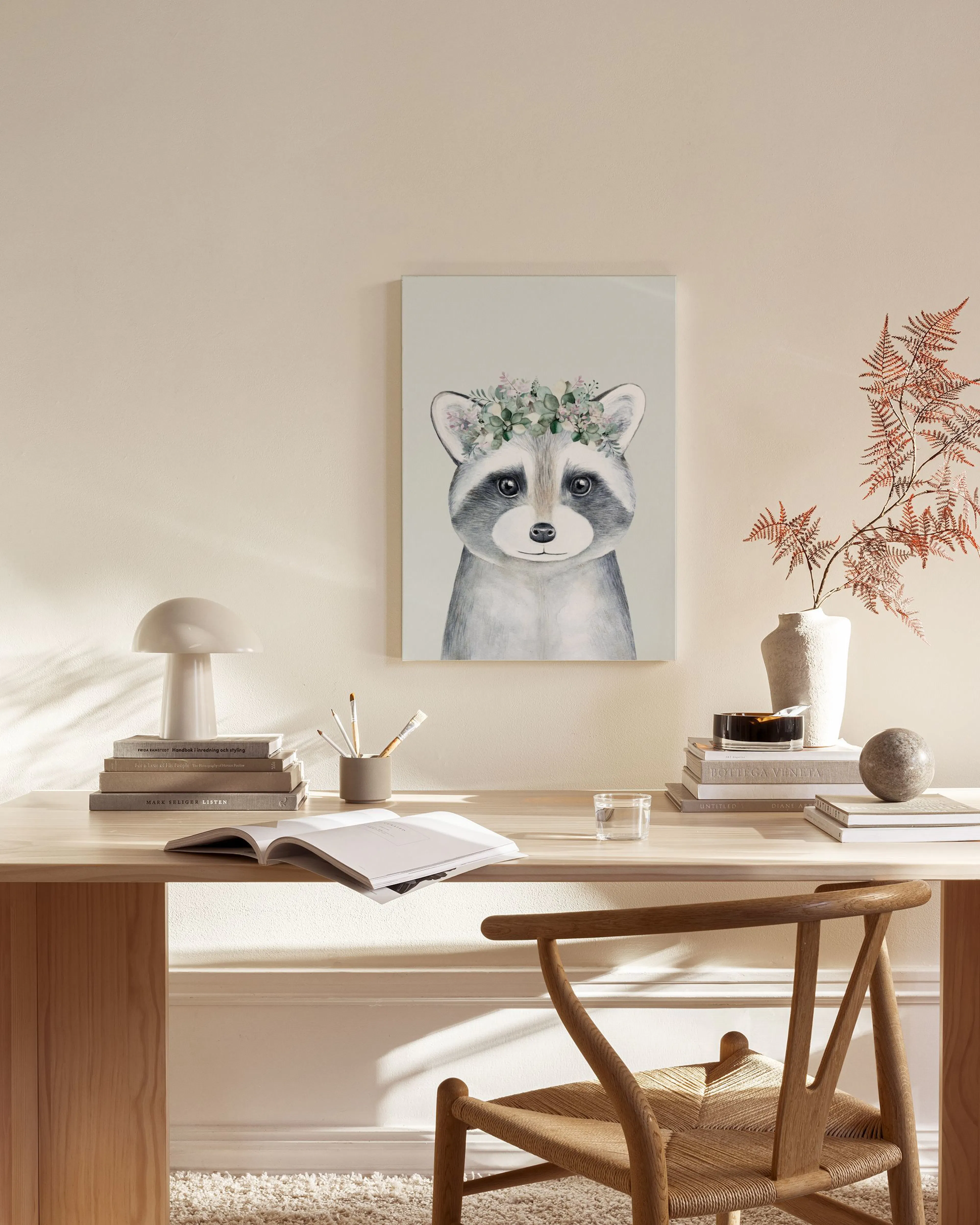 A watercolour print of a raccoon wearing a floral wreath, hanging in a bright, minimalist living room.