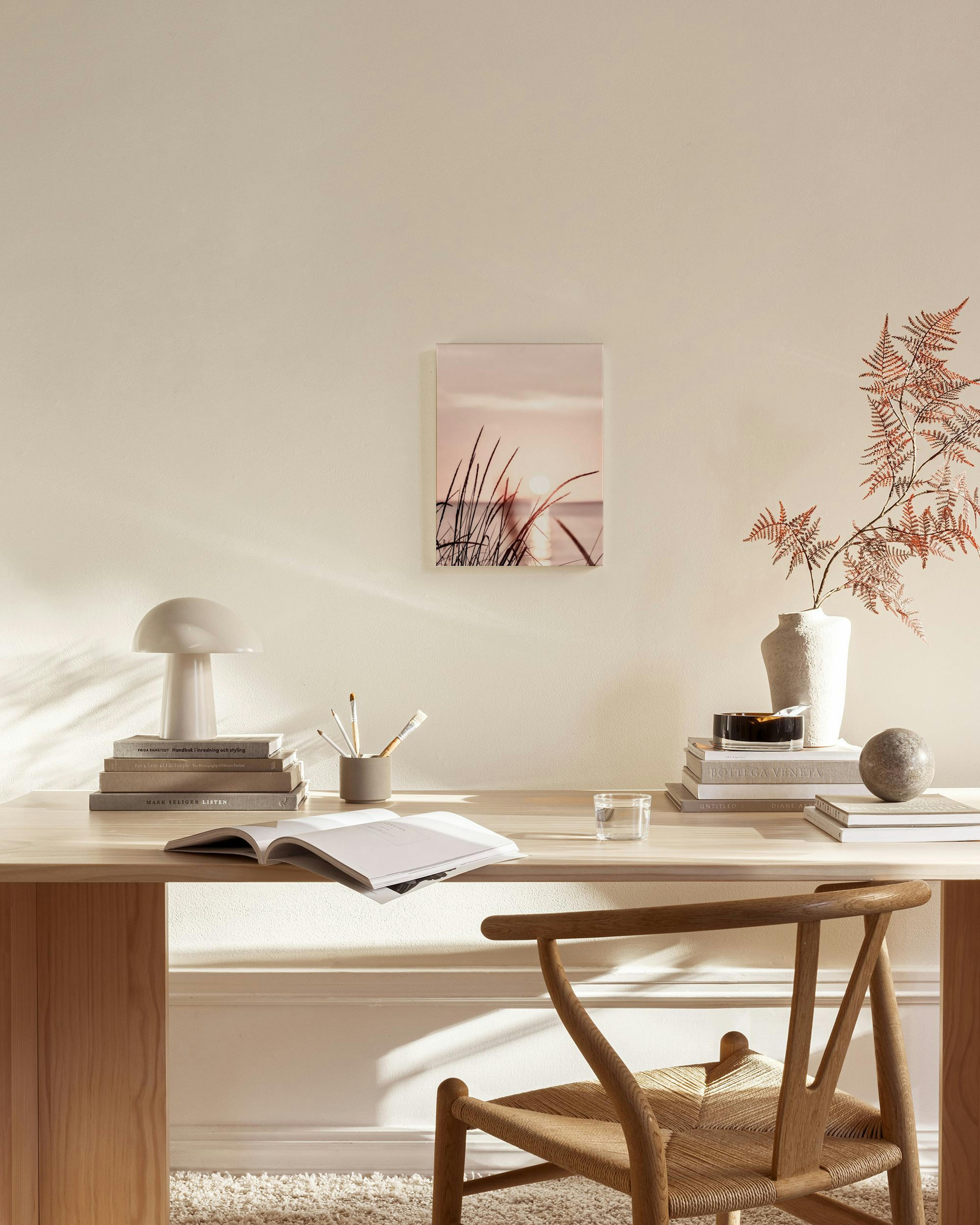 Leinwandbild mit Sonnenuntergang über Wasser und Grashalmen, hängend über einem Sideboard in einem Wohnzimmer.