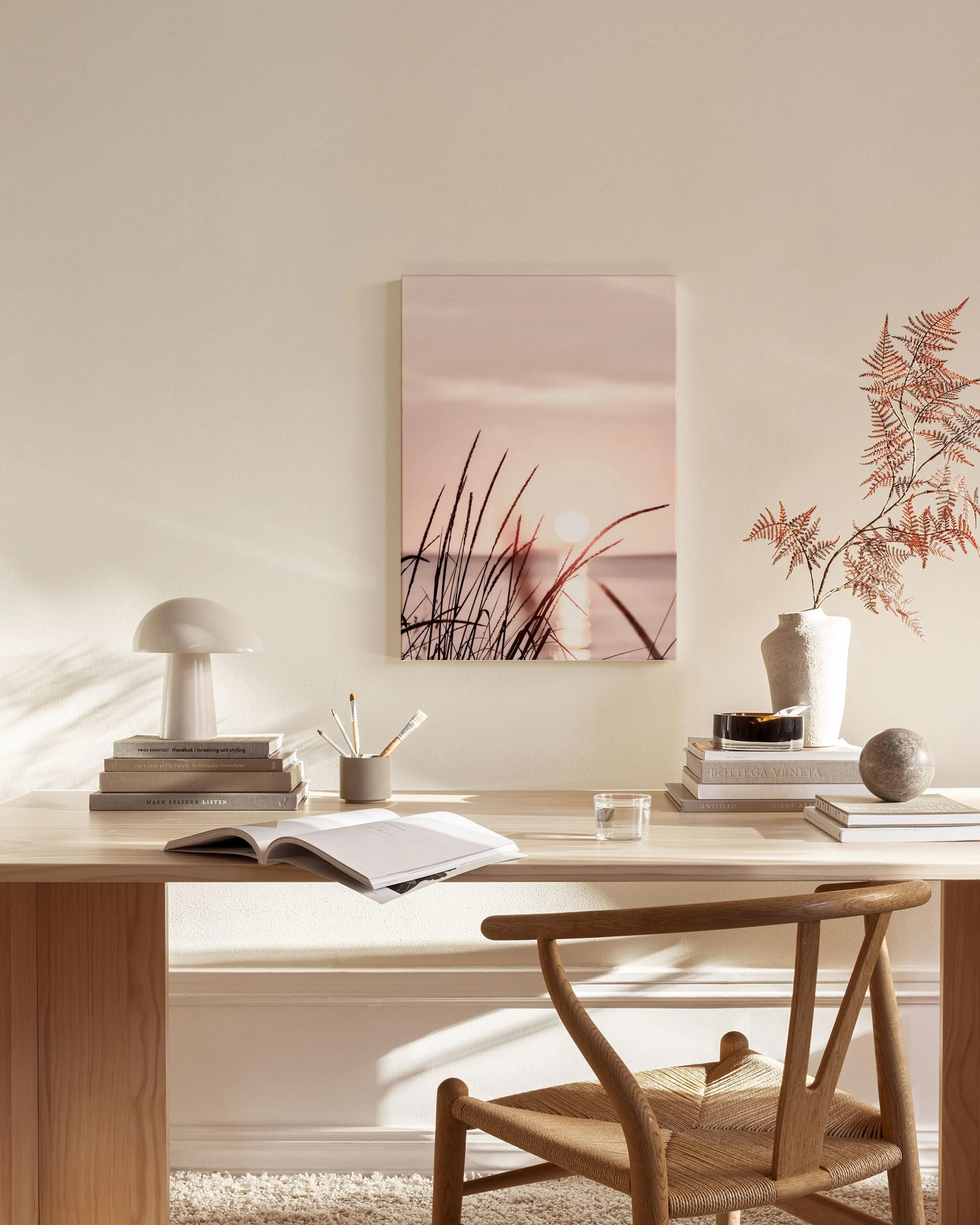 Toile dun coucher de soleil sur leau avec des herbes hautes au premier plan, dans un salon moderne aux tons clairs.