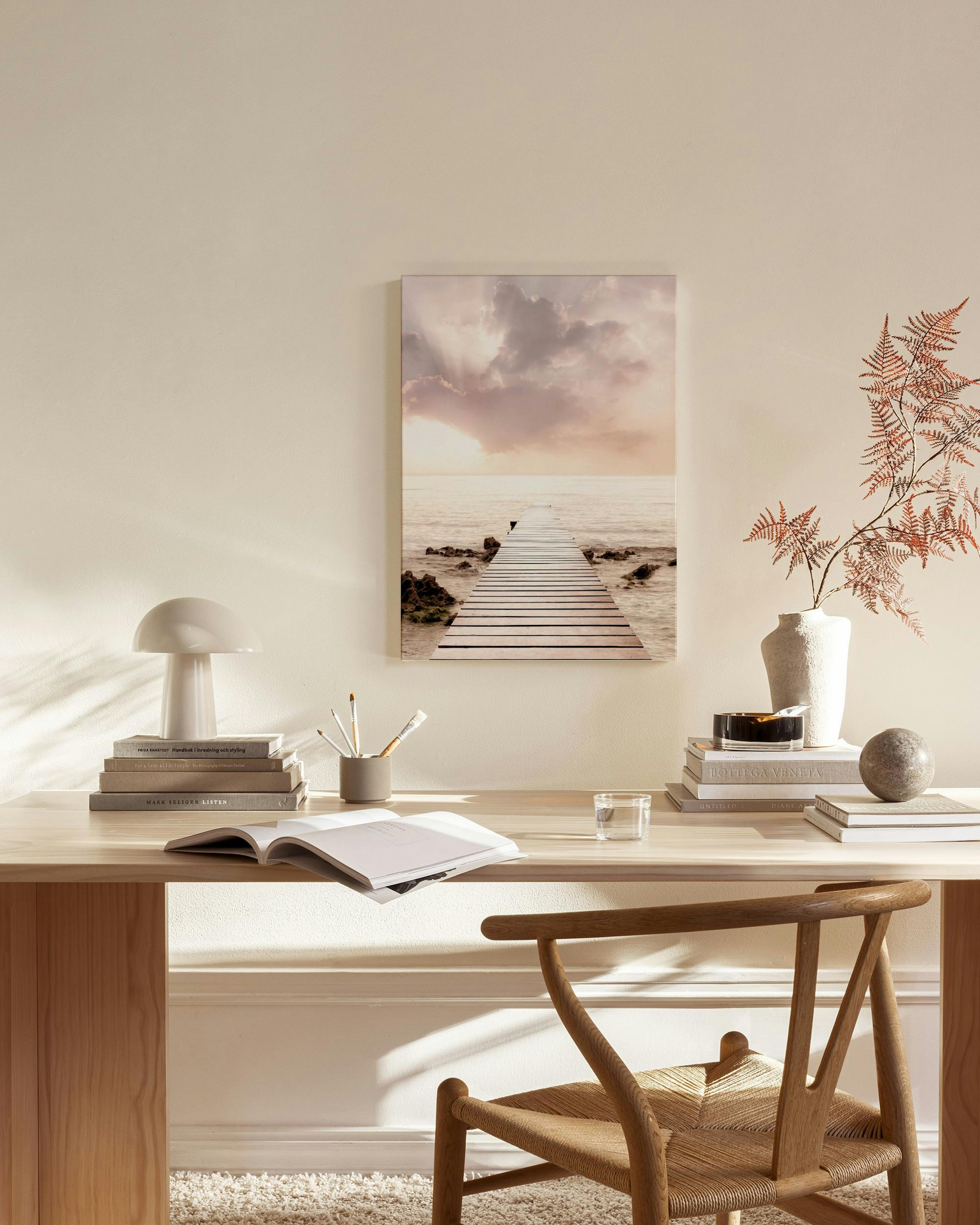 Toile dun quai en bois sur une mer calme au coucher du soleil, suspendue dans un salon moderne aux tons neutres.