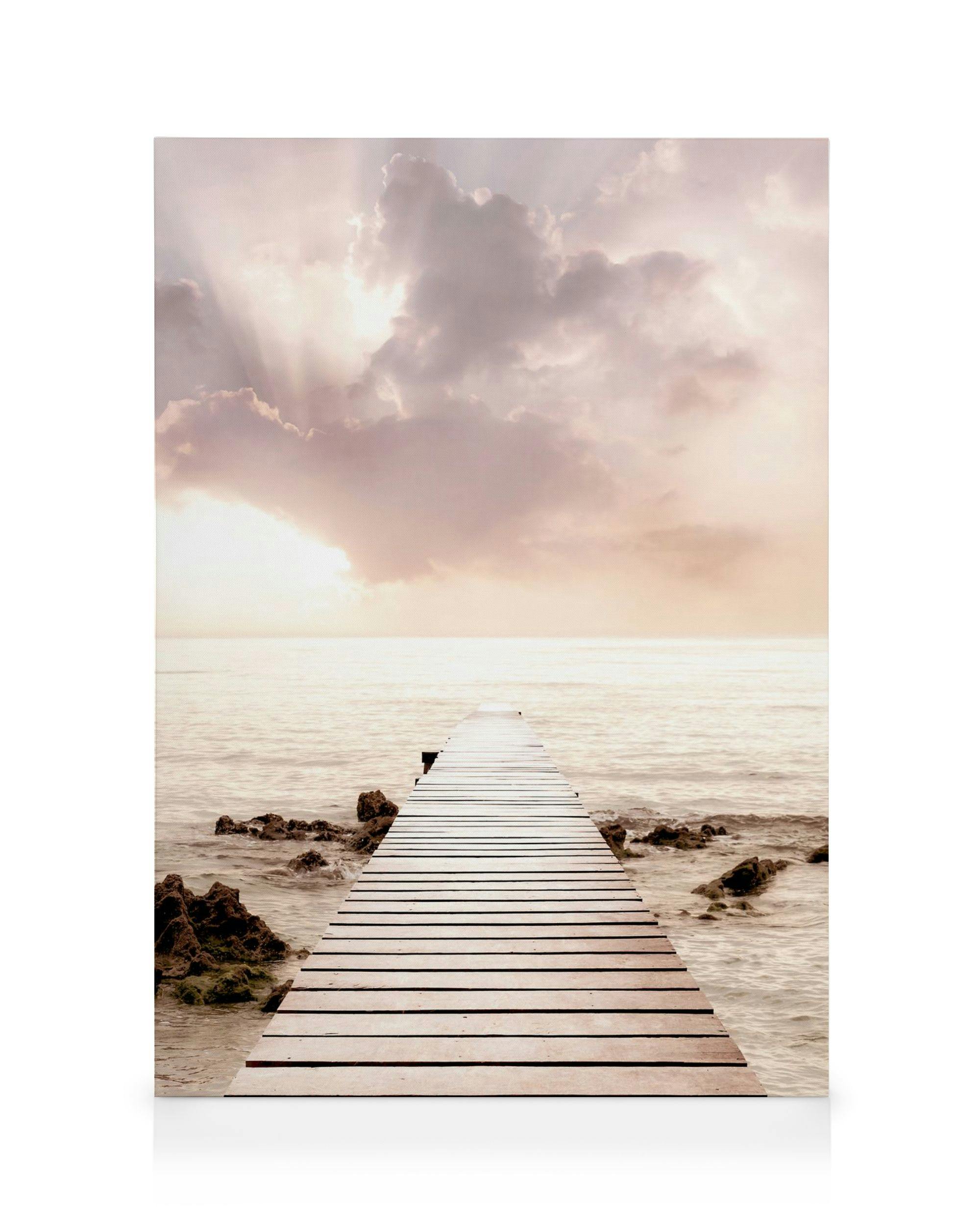 steig die de zee inloopt bij zonsondergang, met roze, witte en blauwe wolken en zonnestralen