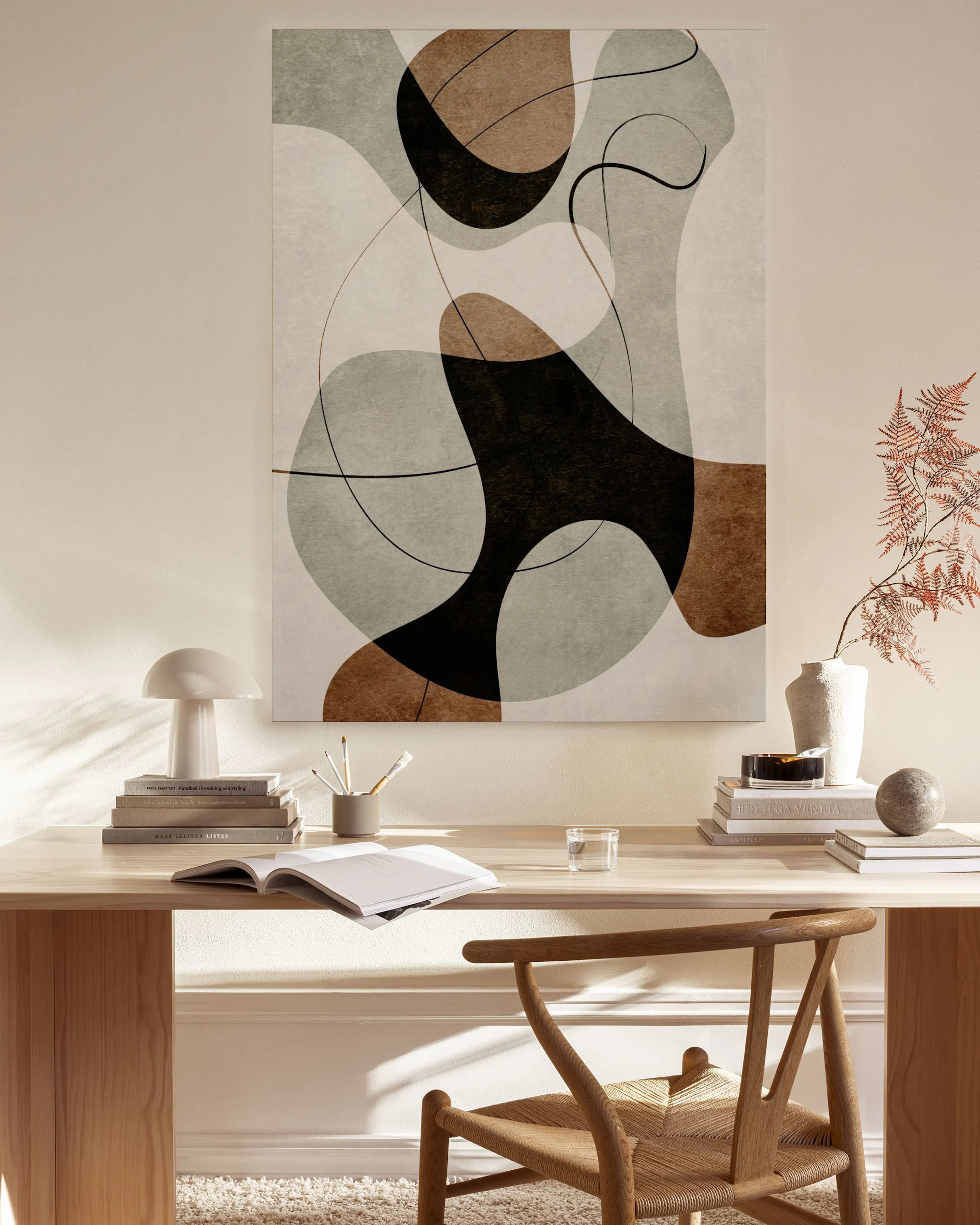 Abstract canvas print with organic shapes in black, brown, and muted grey, outlined by thin lines, hanging in a bright, minimali