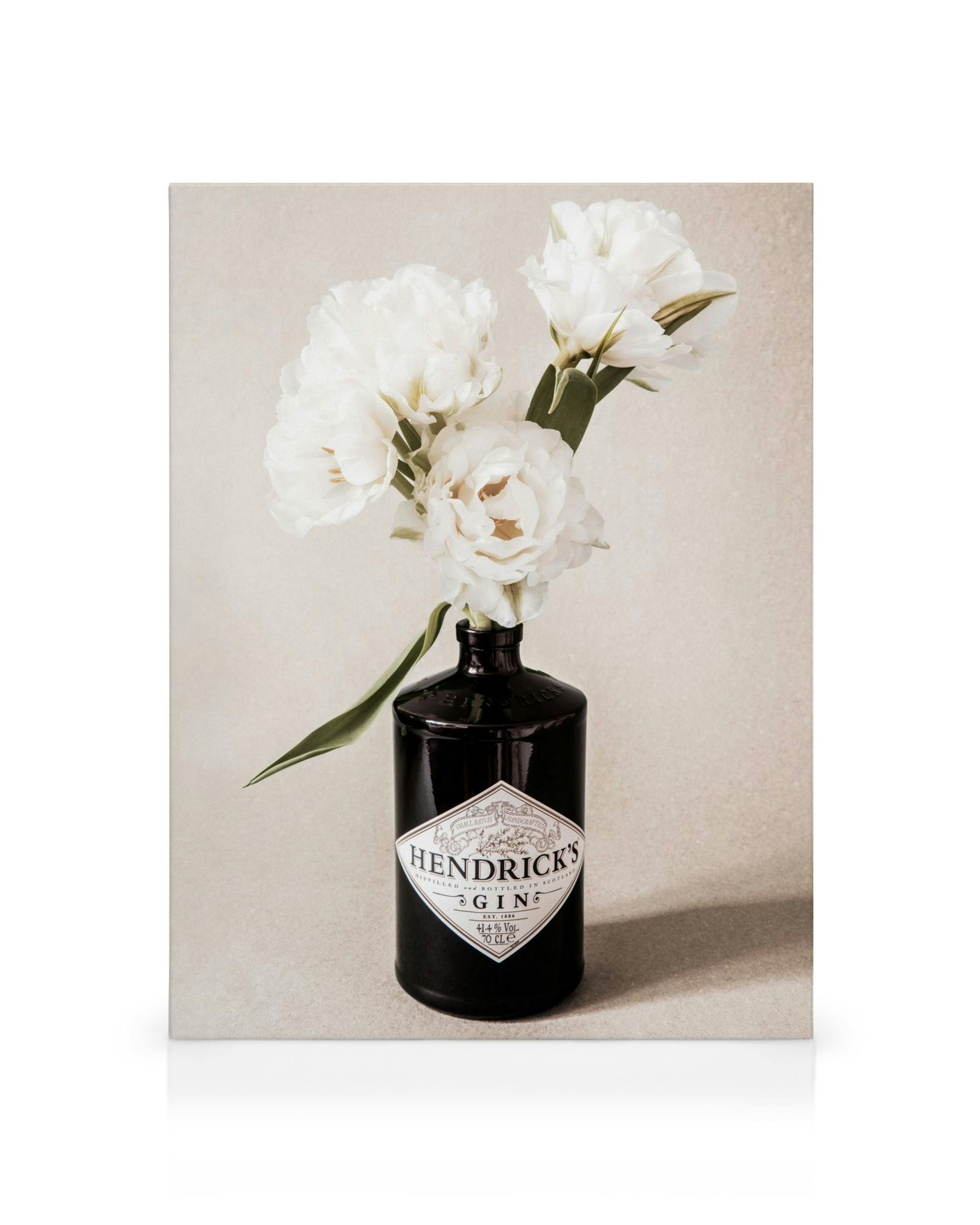 Λευκά λουλούδια σε μαύρο μπουκάλι Gin, σε μπεζ κοκκώδες φόντο, φωτογραφία