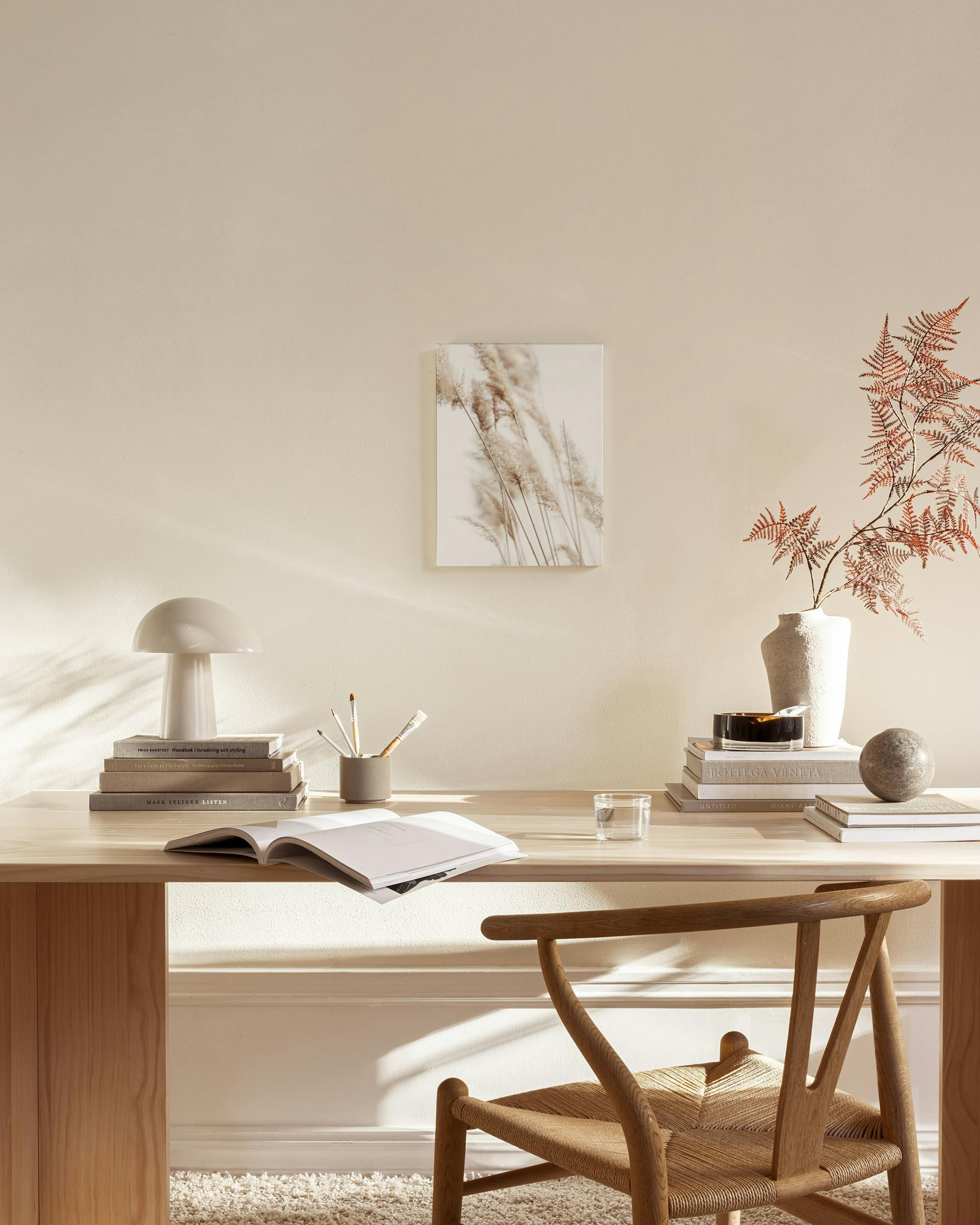 Toile de roseaux séchés beige sur fond clair, suspendue dans un salon minimaliste aux tons neutres.