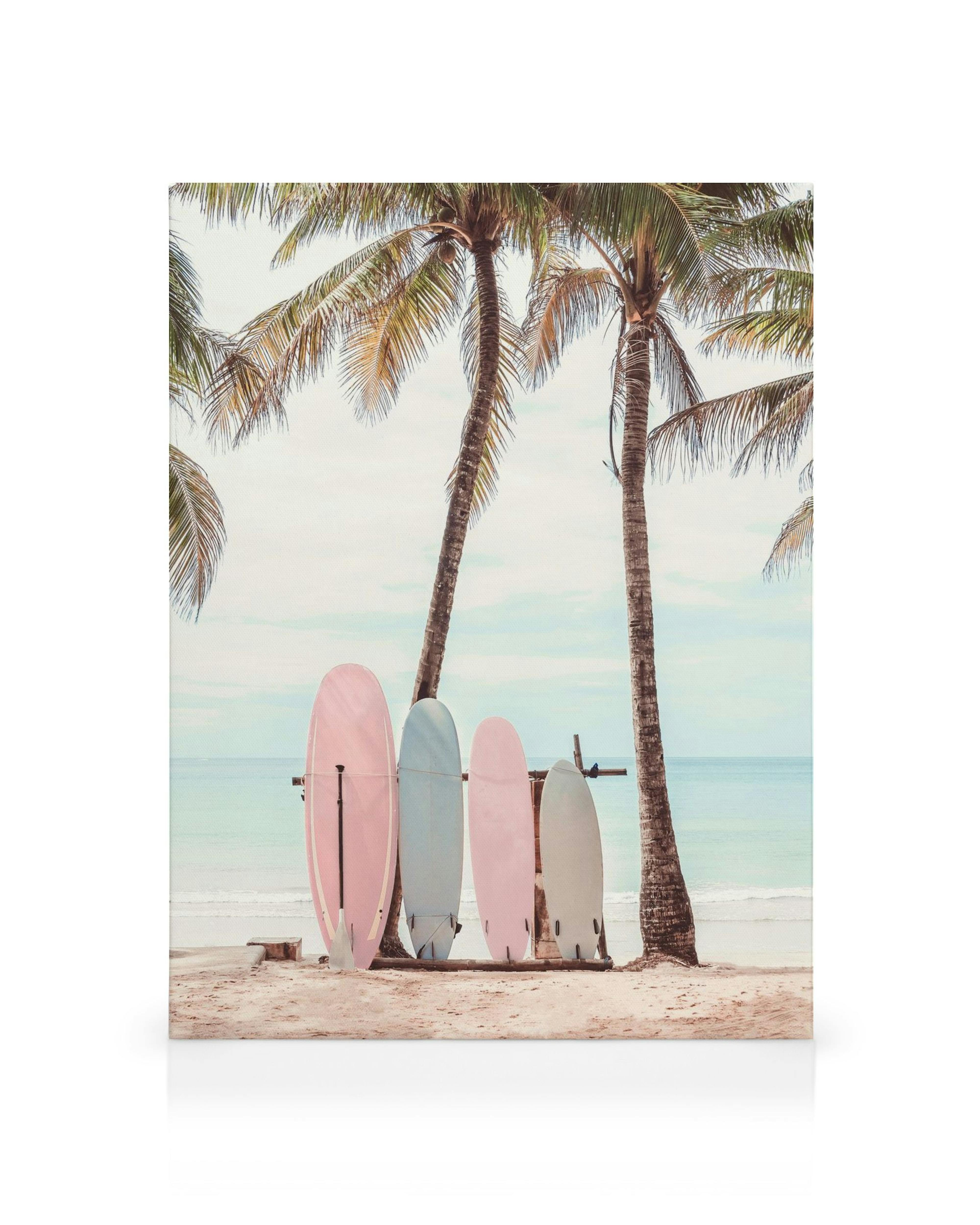 Toile de planches de surf pastel sur plage de sable, palmiers et mer bleue, style côtier.