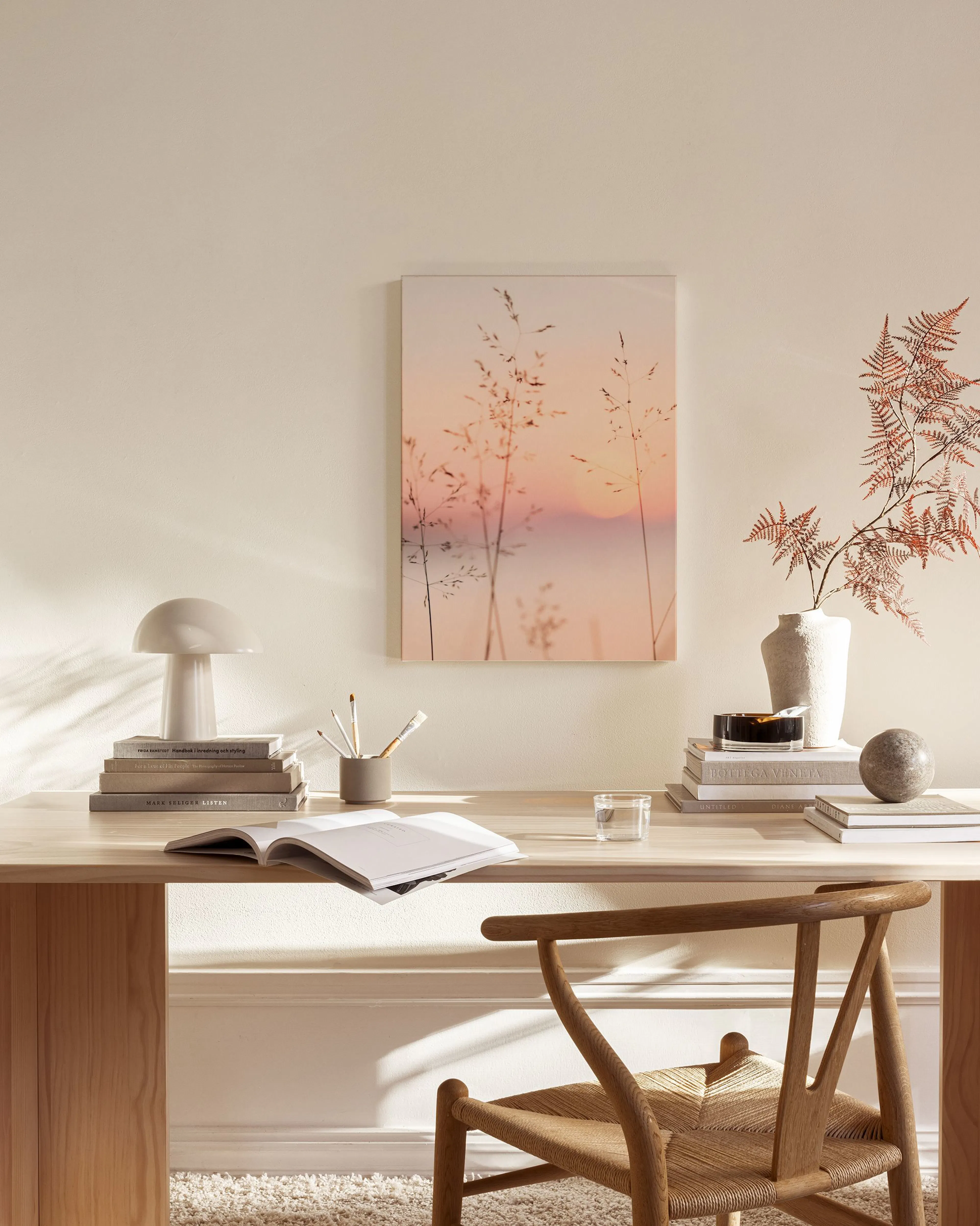 Leinwandbild mit Gräsern vor rosa-goldenem Sonnenuntergang, hängt im Wohnzimmer über einem Sideboard.