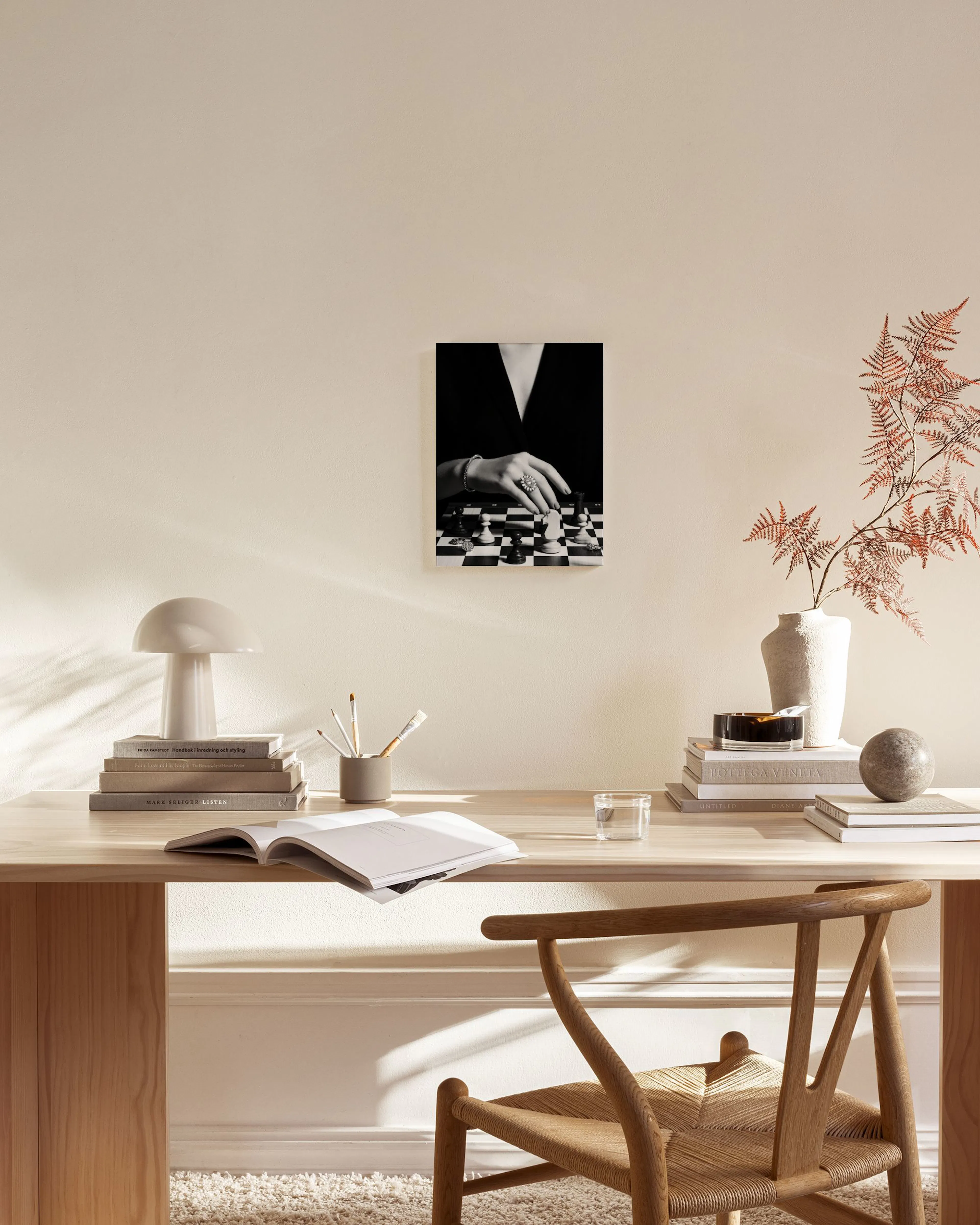 Black and white print of a womans hand with a ring moving a chess piece, hanging in a modern living room.