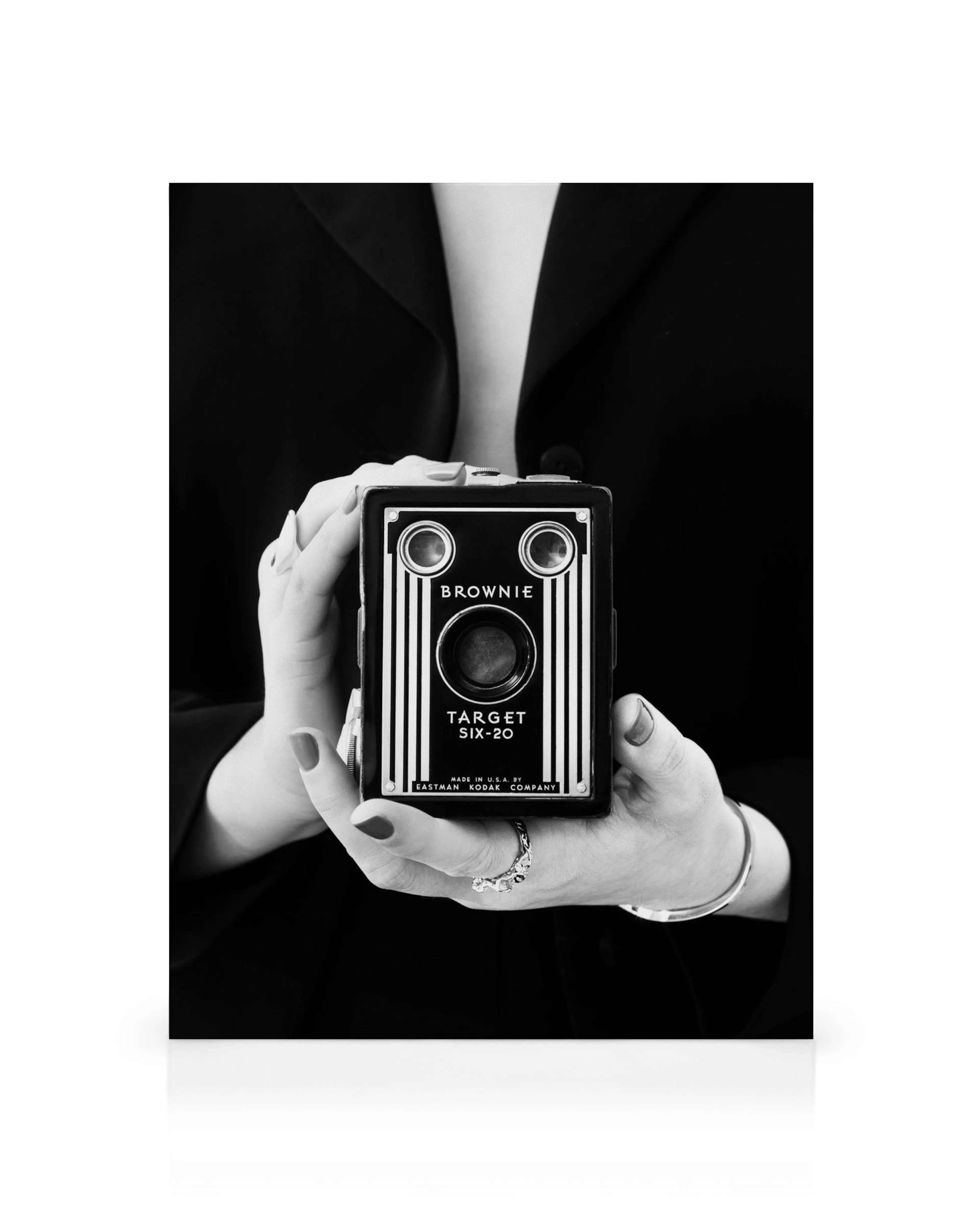 Monochrome canvas print of hands holding a vintage Brownie Target Six-20 camera against a black background.
