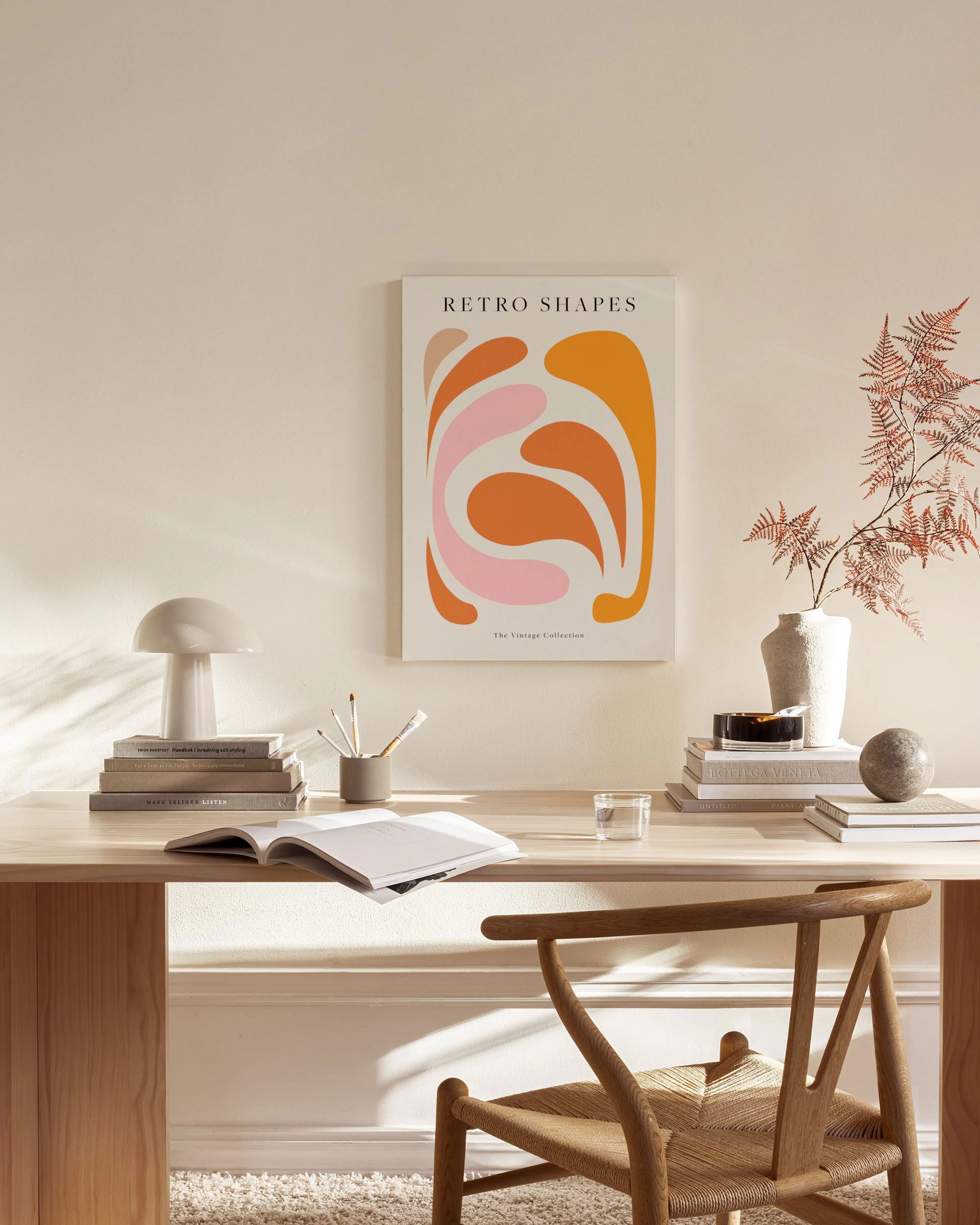 Canvastavla med abstrakta former i rosa, orange och beige, hängande i ett ljust vardagsrum med trädetaljer.