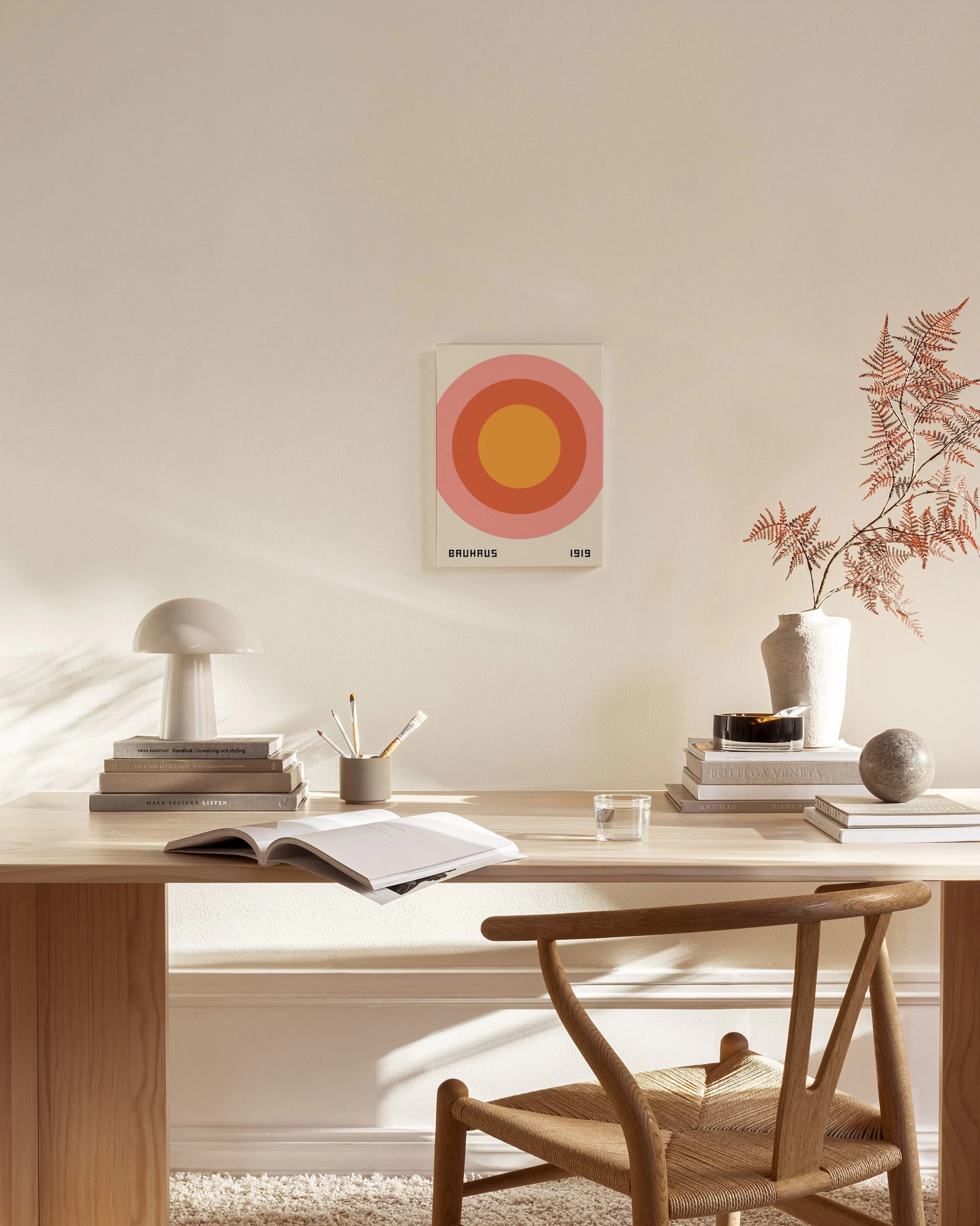 A Bauhaus 1919 print with concentric orange and pink circles, hanging in a minimalist living room above a wooden console.