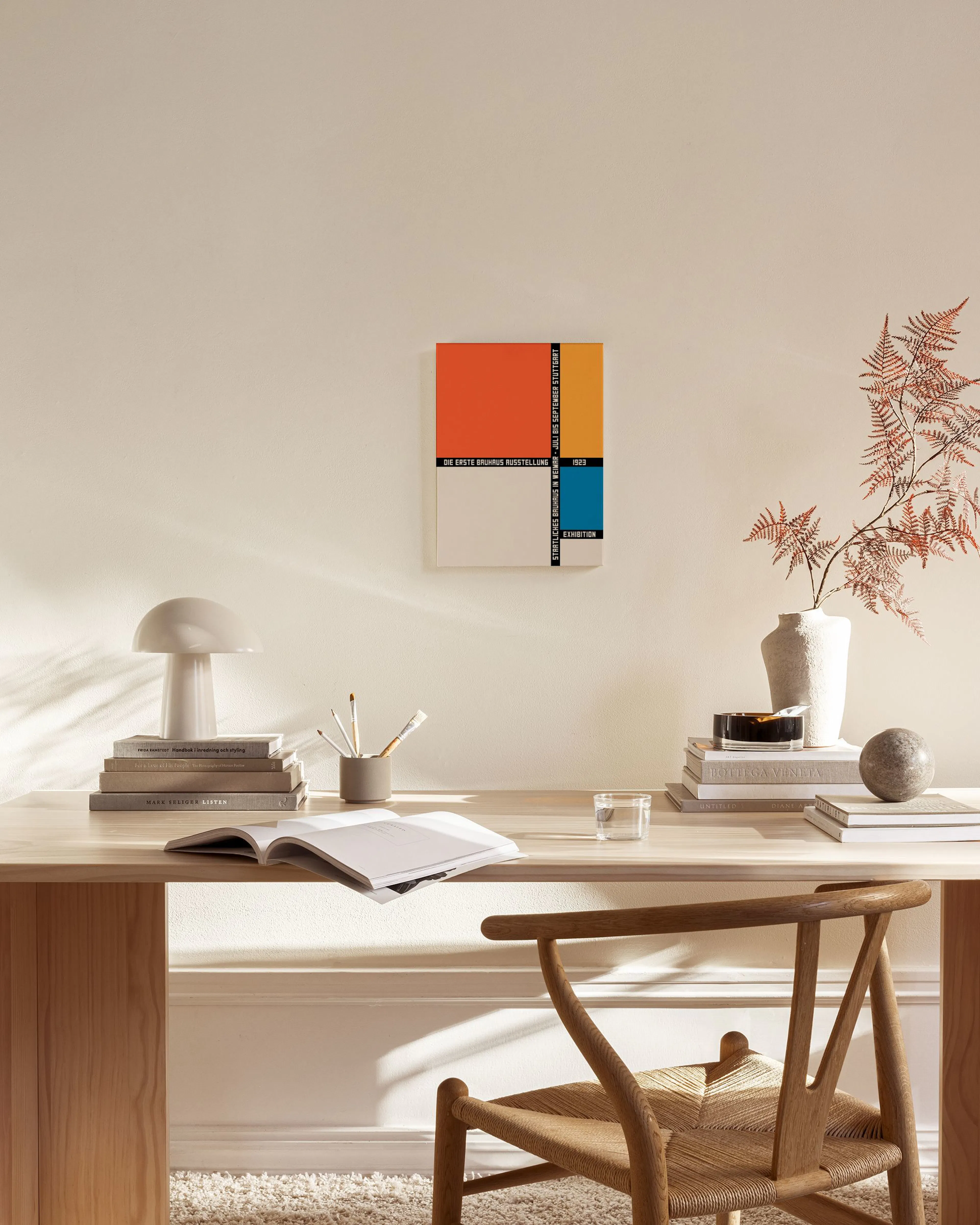 Una stampa su tela con colori arancione, giallo e blu, appesa in un soggiorno moderno sopra un mobile basso in legno.