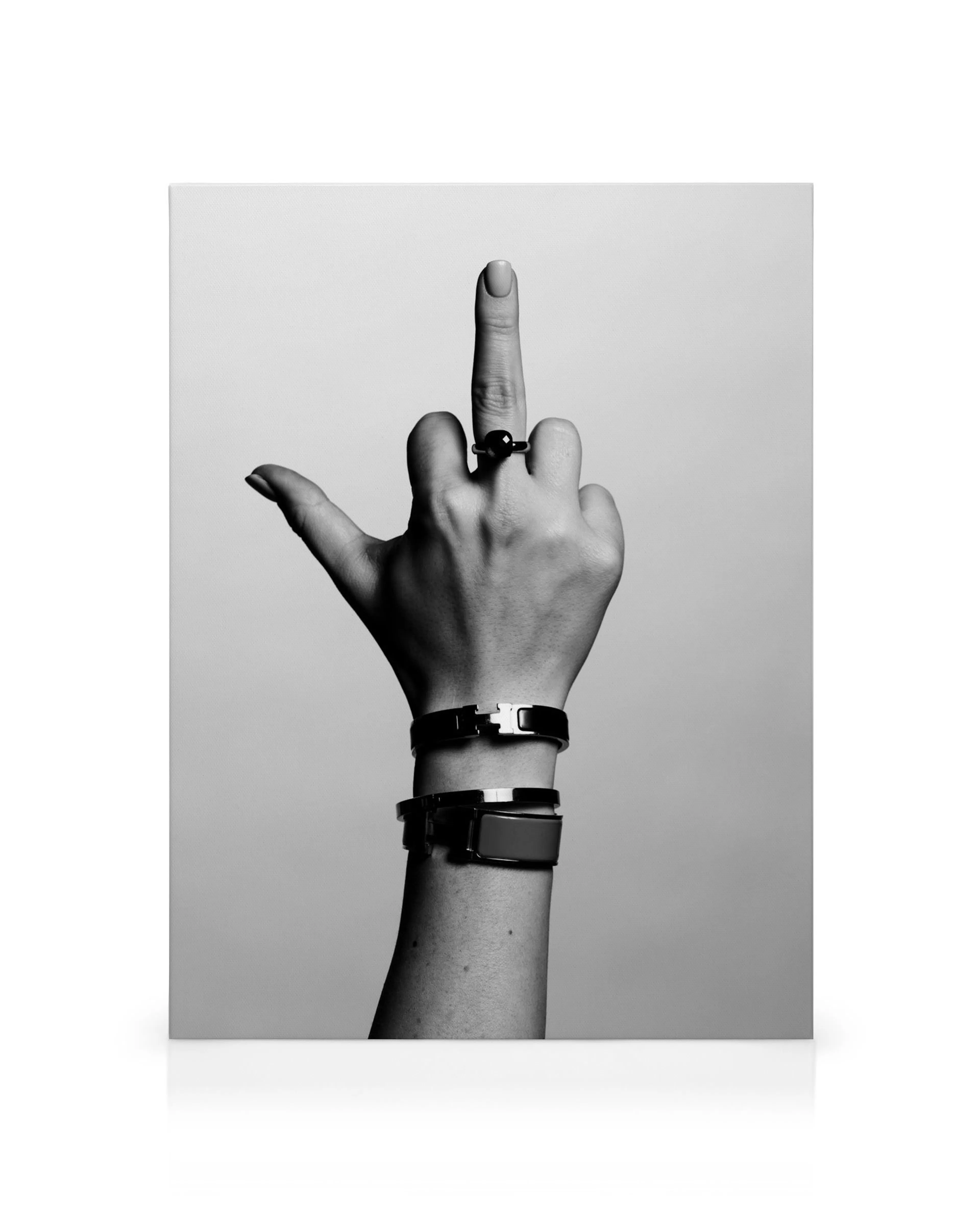 Schwarz-weiß-Leinwandbild einer Hand, die den Mittelfinger zeigt, mit Armbändern und Ring. Provokative Kunst.