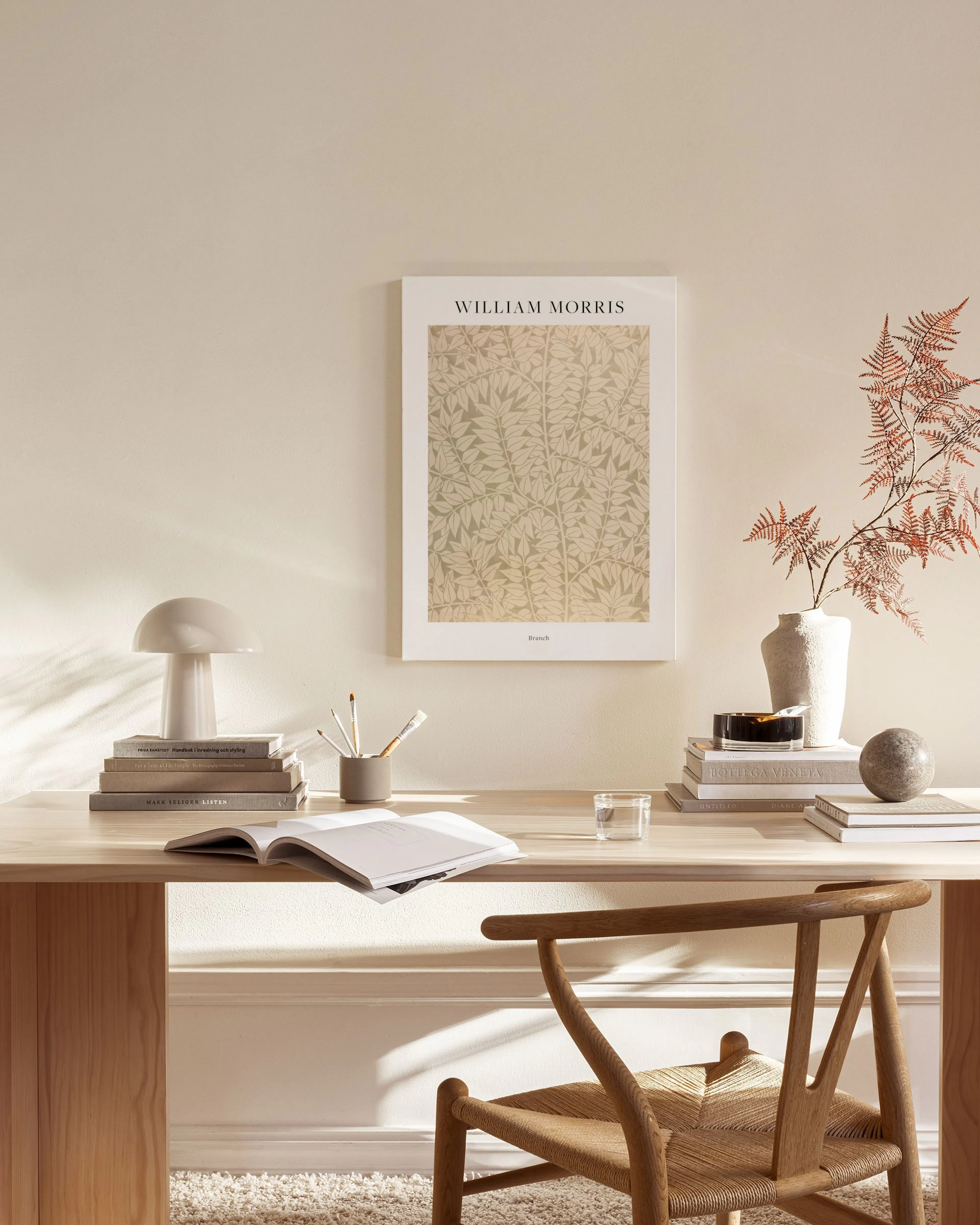 Canvastavla med William Morris Branches-mönster i beiga nyanser, hängandes i ett ljust vardagsrum med trädetaljer.