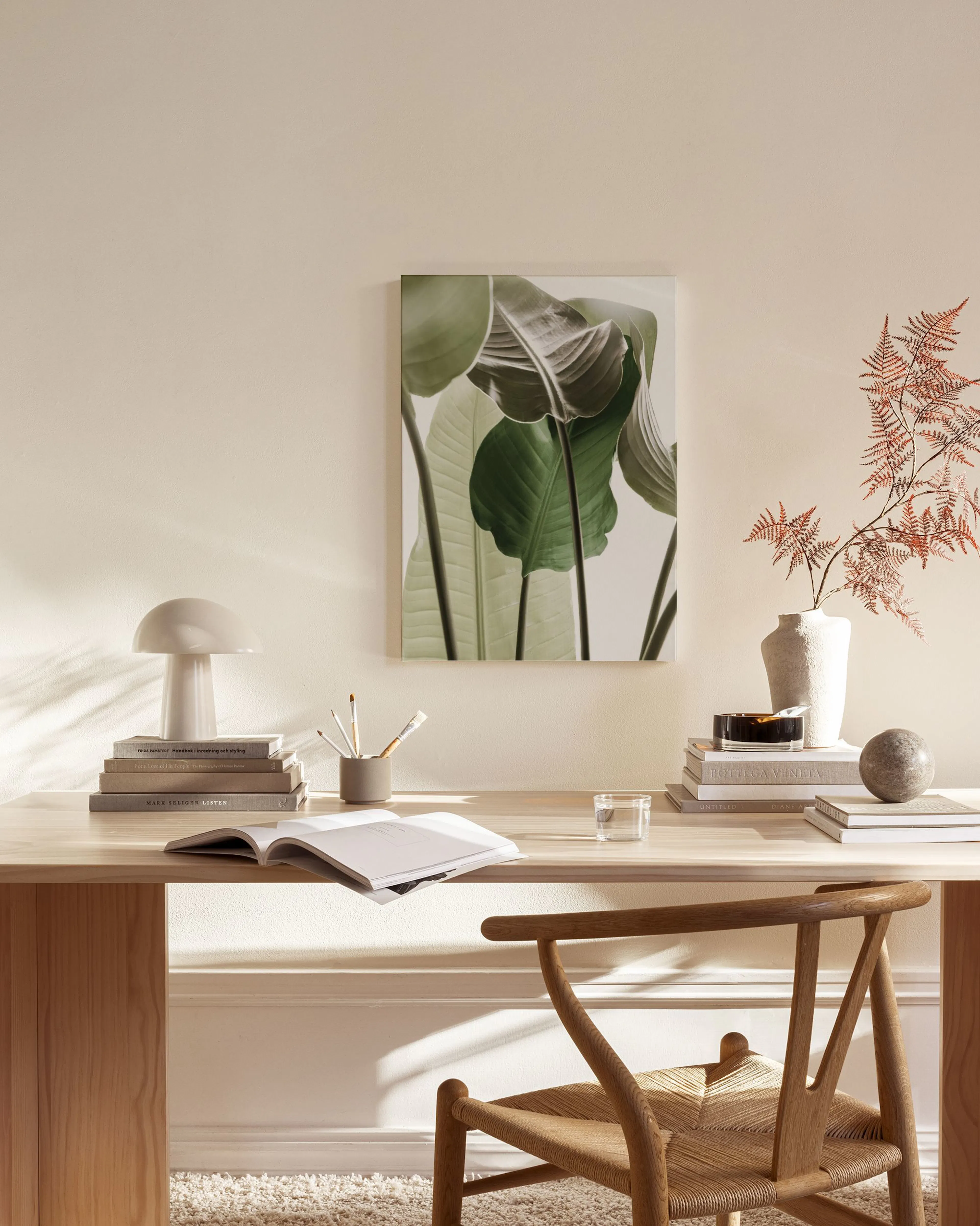 Toile de feuilles tropicales vertes, accrochée au-dessus dun meuble bas clair dans un salon minimaliste.