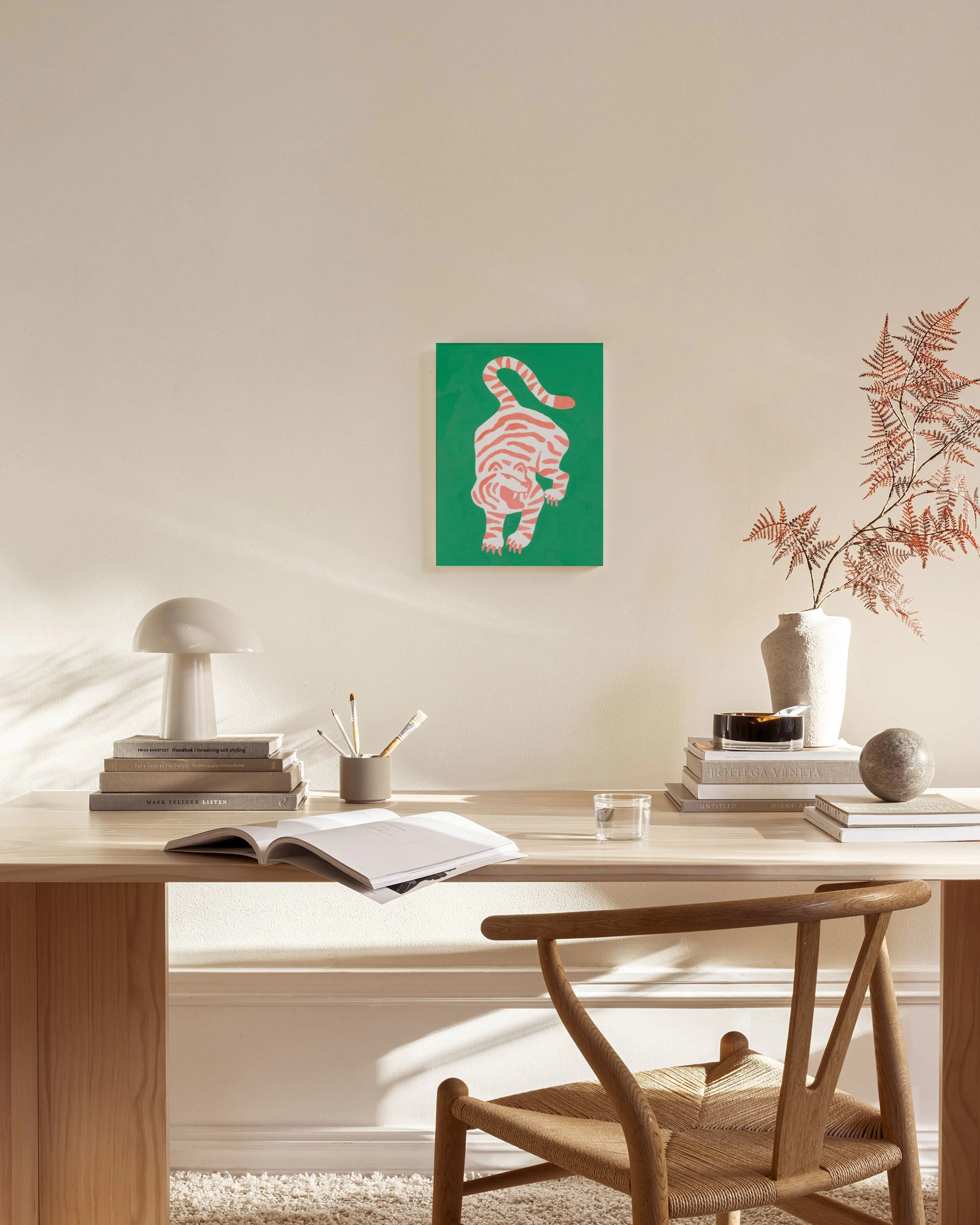 A vibrant green canvas print of an orange and white striped tiger, hanging above a timber console table in a modern living room.