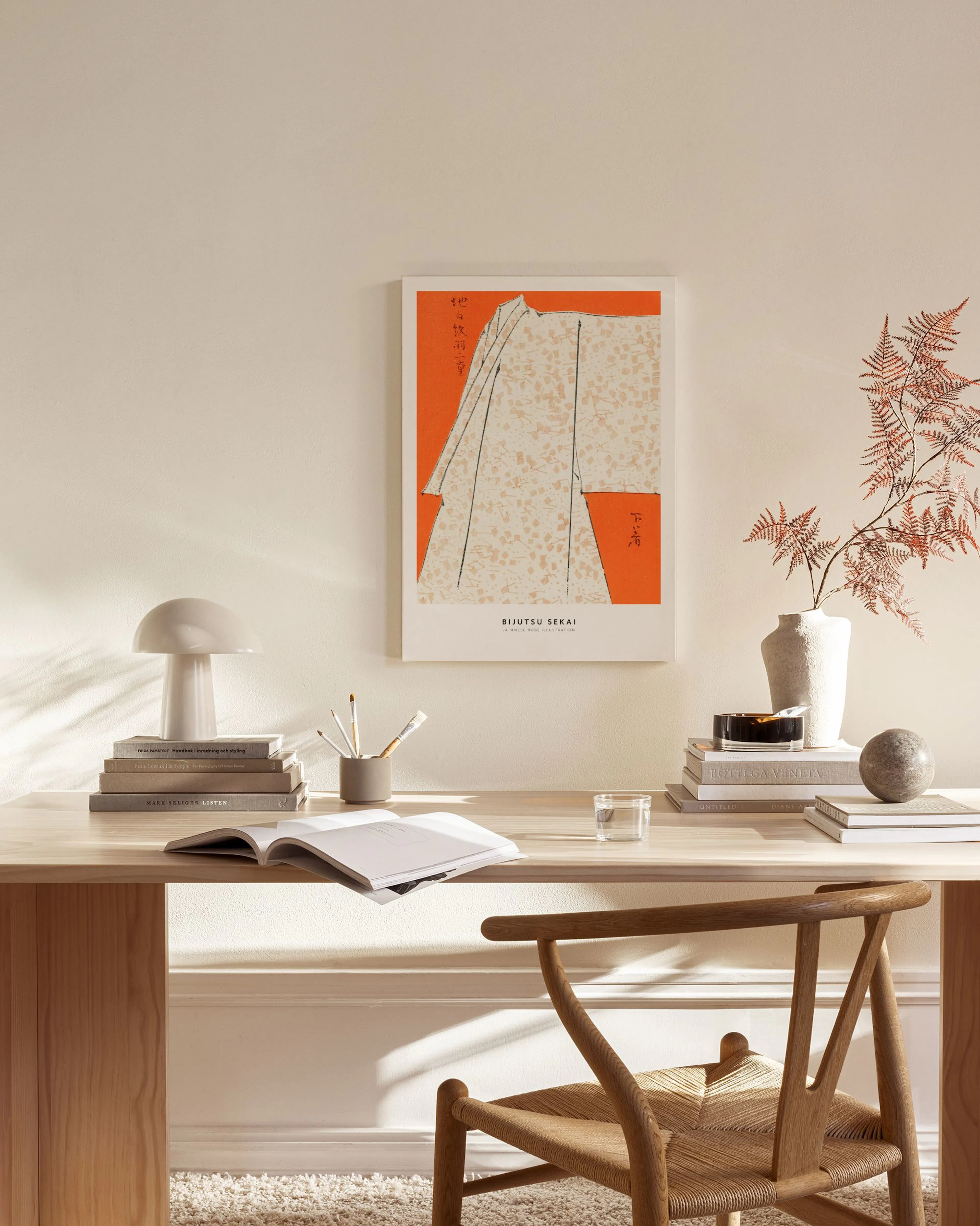 Japanilainen kanvaasi, jossa on oranssilla pohjalla beige kimono, ripustettuna olohuoneen seinällä.
