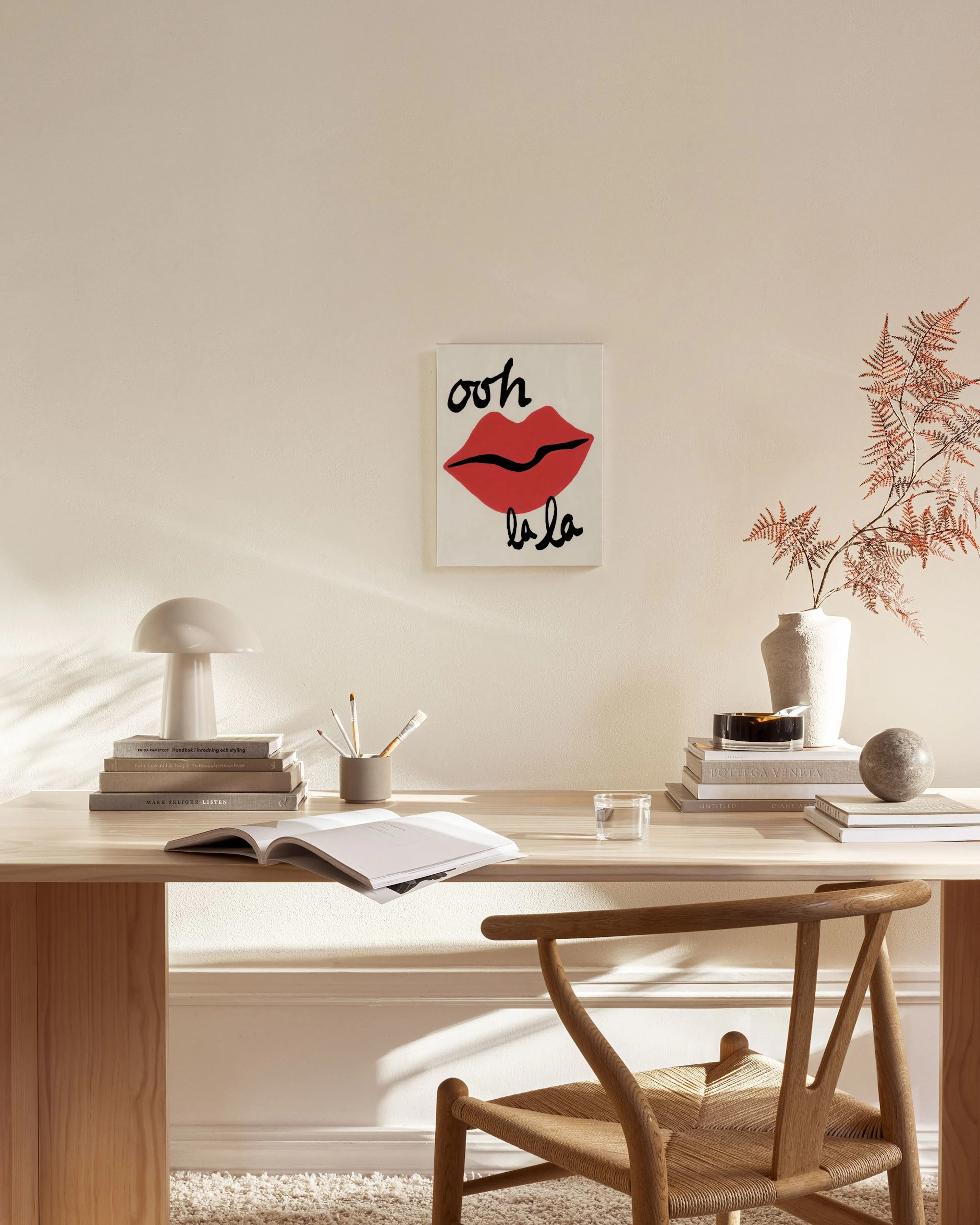 Canvas met rode lippen en de tekst ooh la la, hangend in een lichte woonkamer boven een houten dressoir.