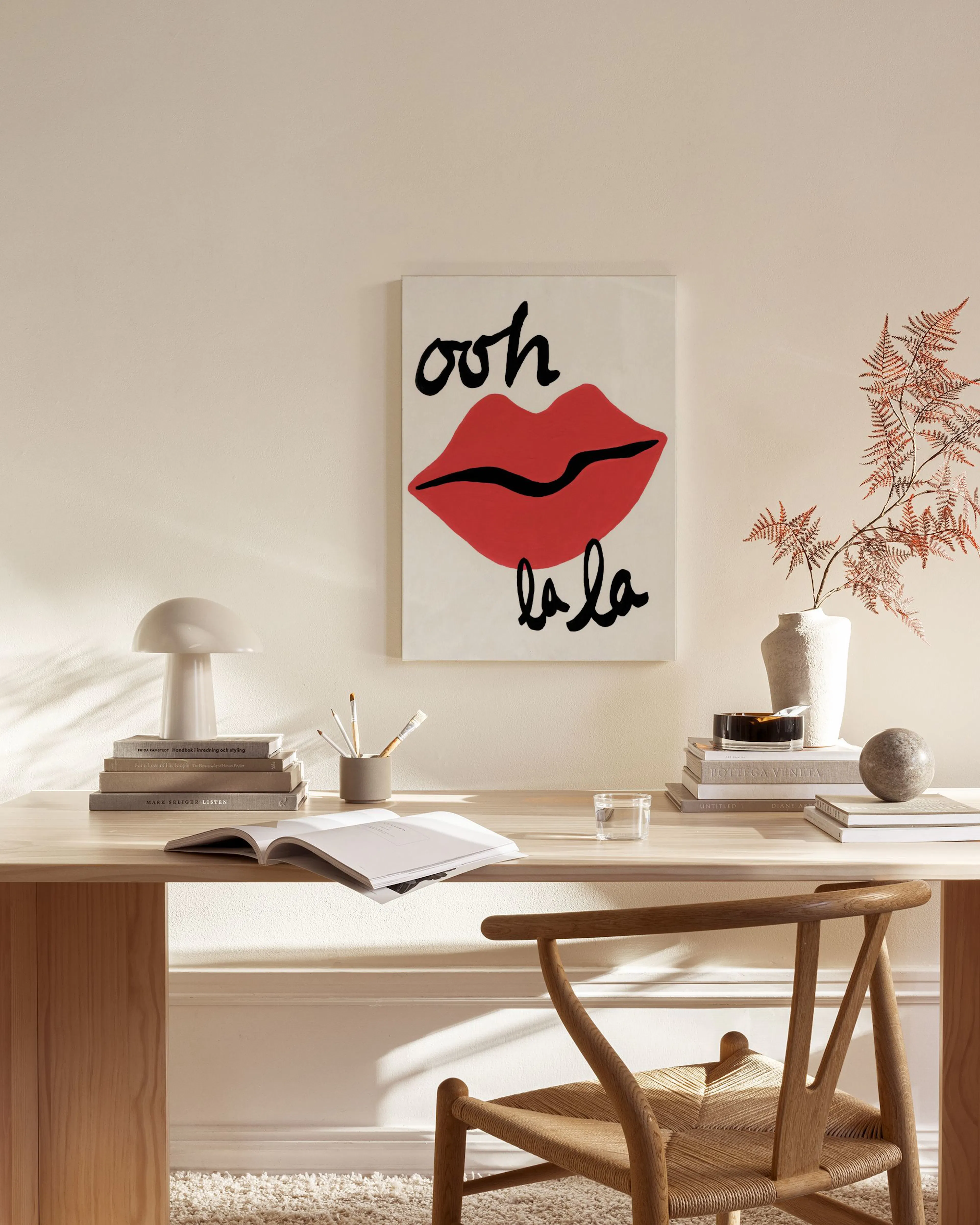 A pop art print of red lips and black script ooh la la hanging in a minimalist living room.