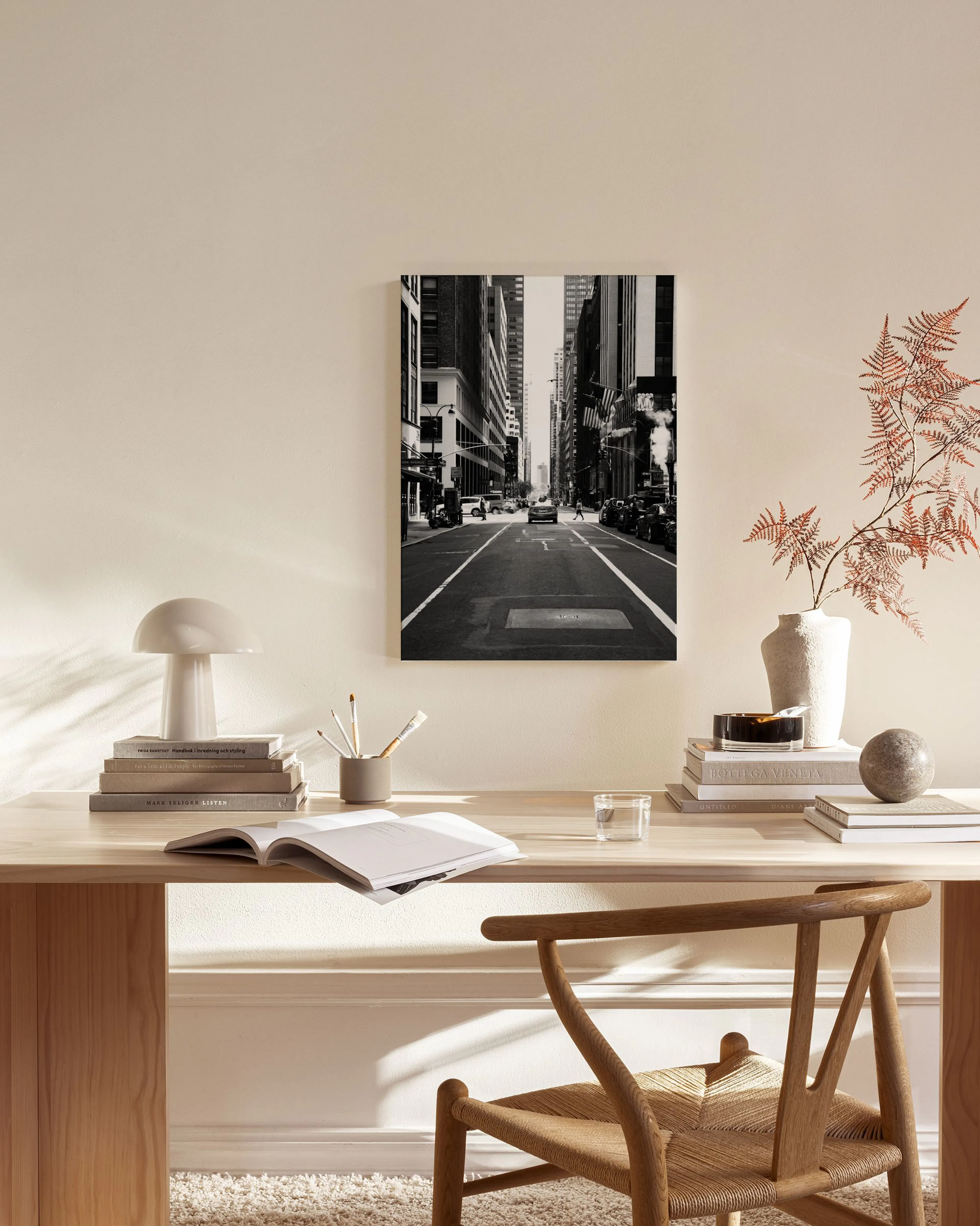 Schwarz-weißes Leinwandbild einer New Yorker Straße mit Wolkenkratzern und Autos, hängt in einem modernen Wohnzimmer.