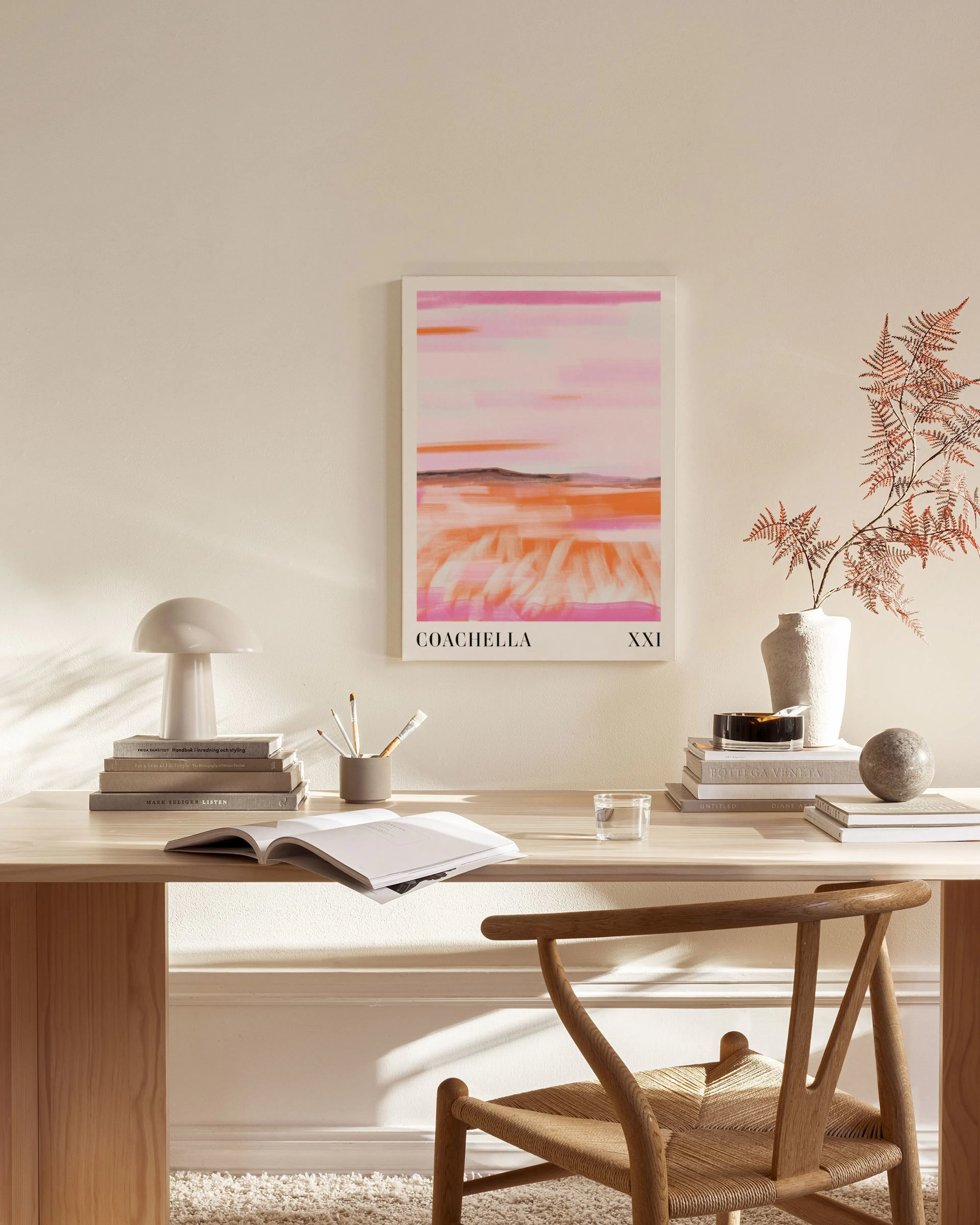 A canvas print with pink and orange abstract landscape, featuring COACHELLA XXI text, displayed in a modern living room.