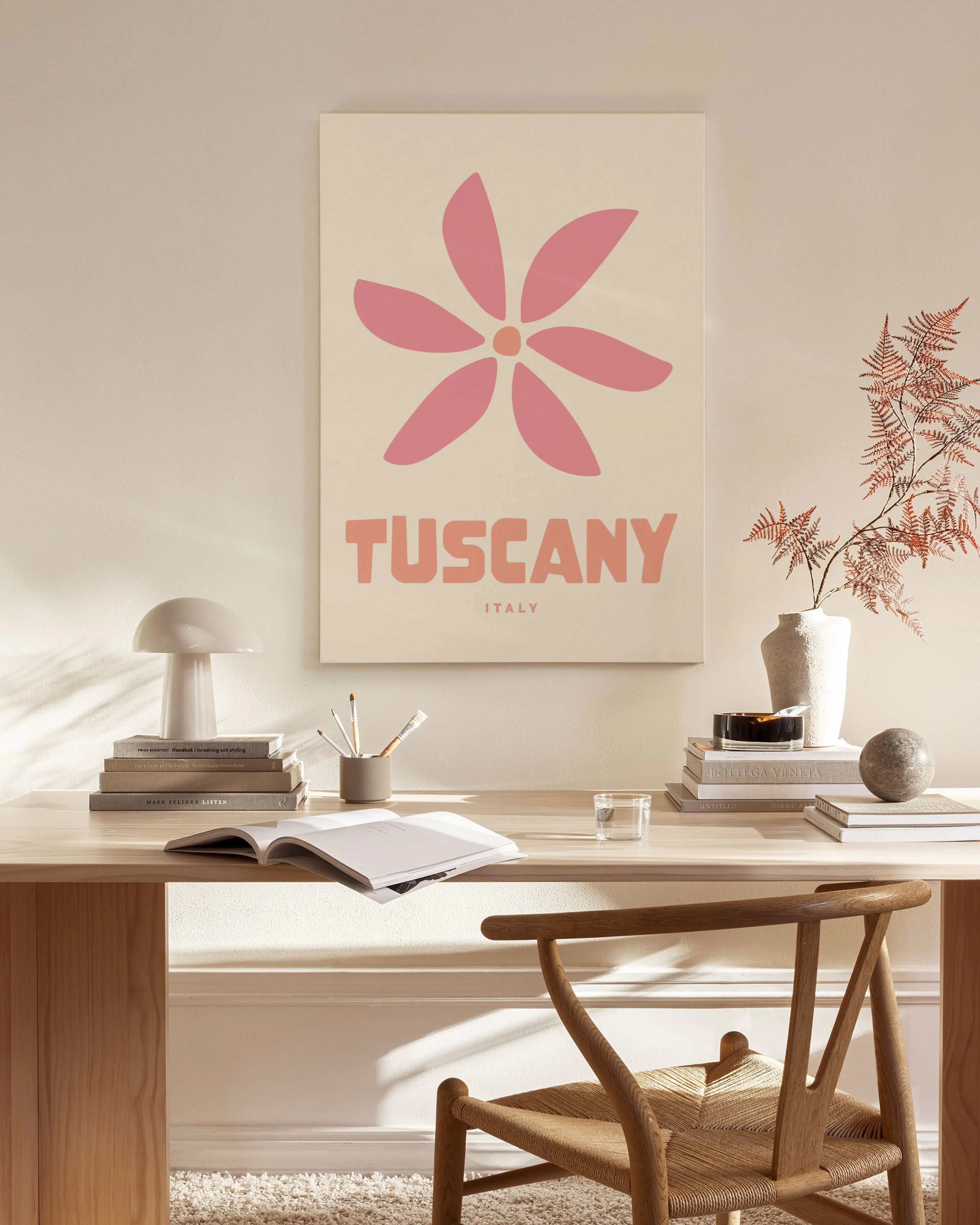 Toile Tuscany Italy avec fleur rose sur fond beige, accrochée dans un salon lumineux au-dessus dun banc en bois.